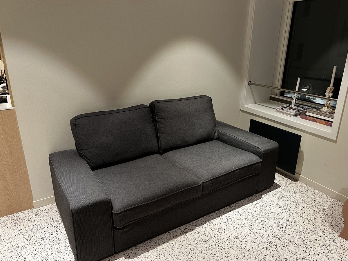 Sofa på motsatt side av hylle og bord. Galleribilde