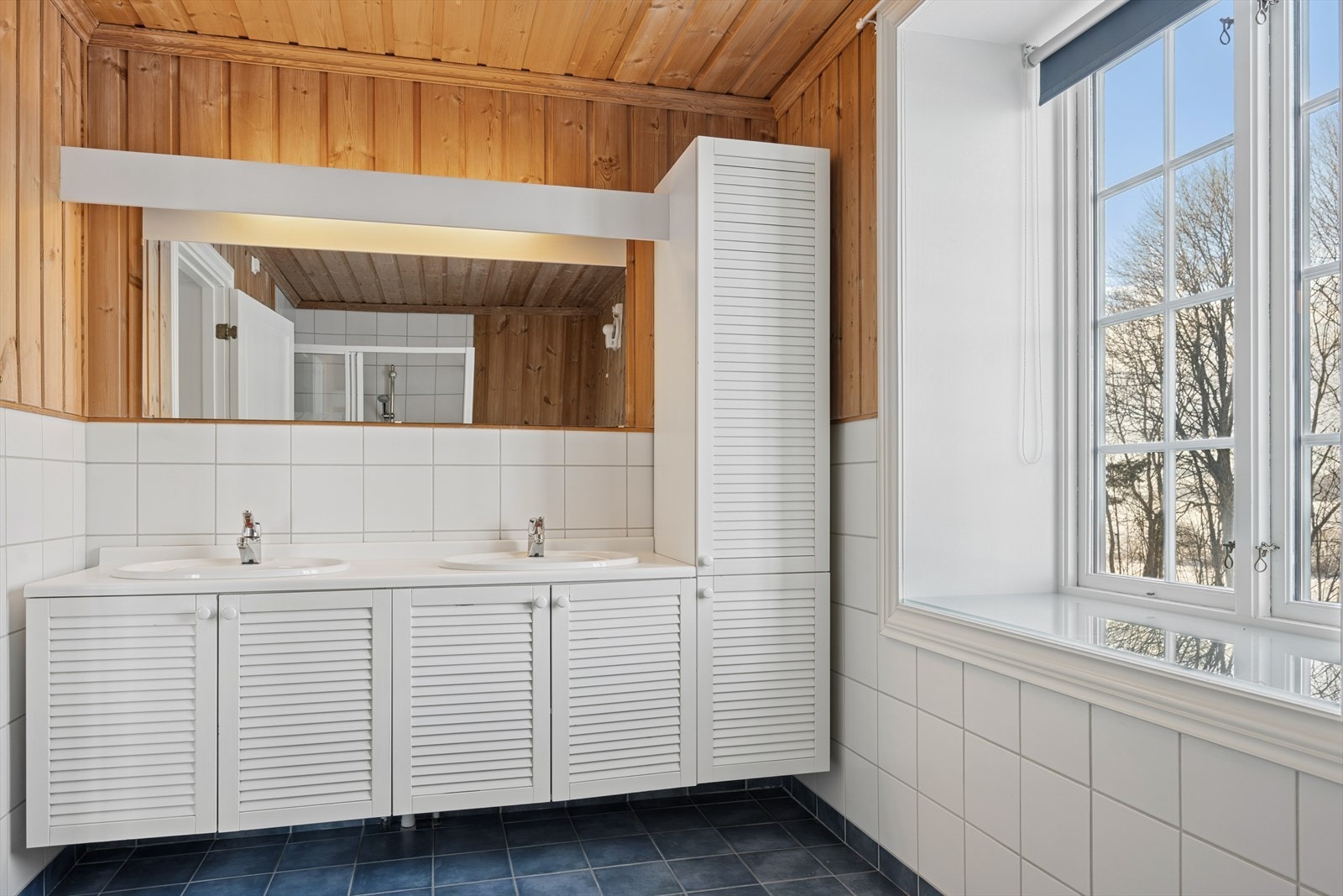 Baderomsinnredningen har sjalusifronter og en laminert benkeplate med to nedfelte servanter. Galleribilde