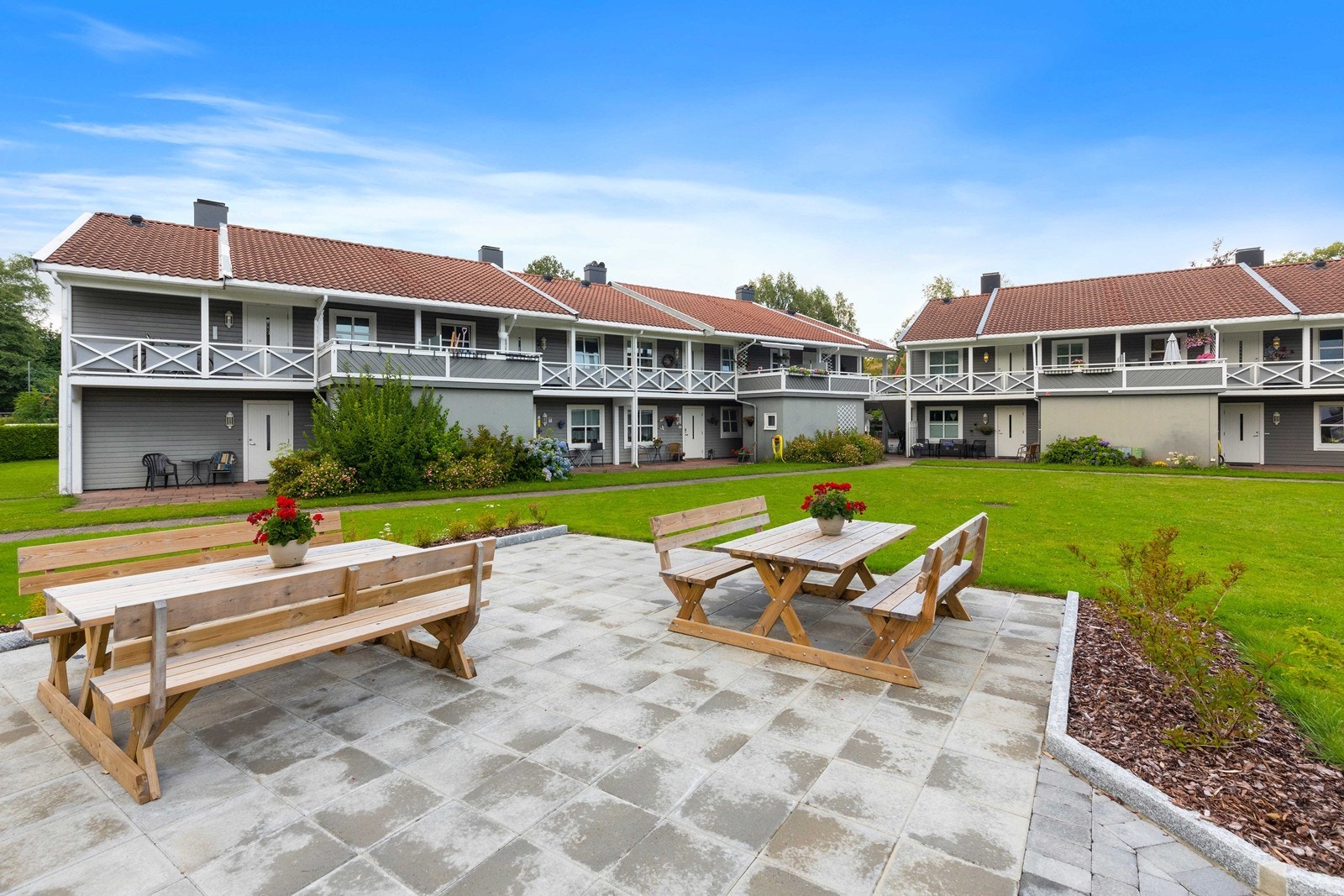 Pent opparbeidet med sitteplasser, gressplen og diverse beplantning. Galleribilde