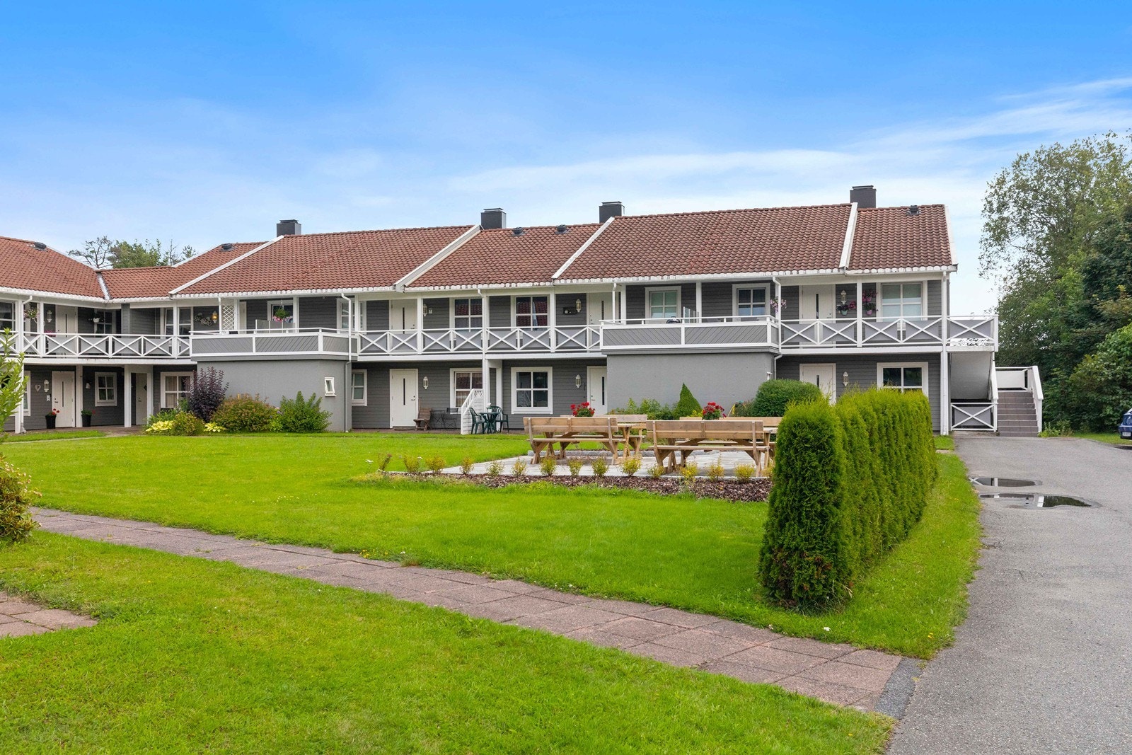 Leiligheten ligger i et populært borettslag, med pent opparbeidet uteareal. Sommerbilde av fasade. Galleribilde