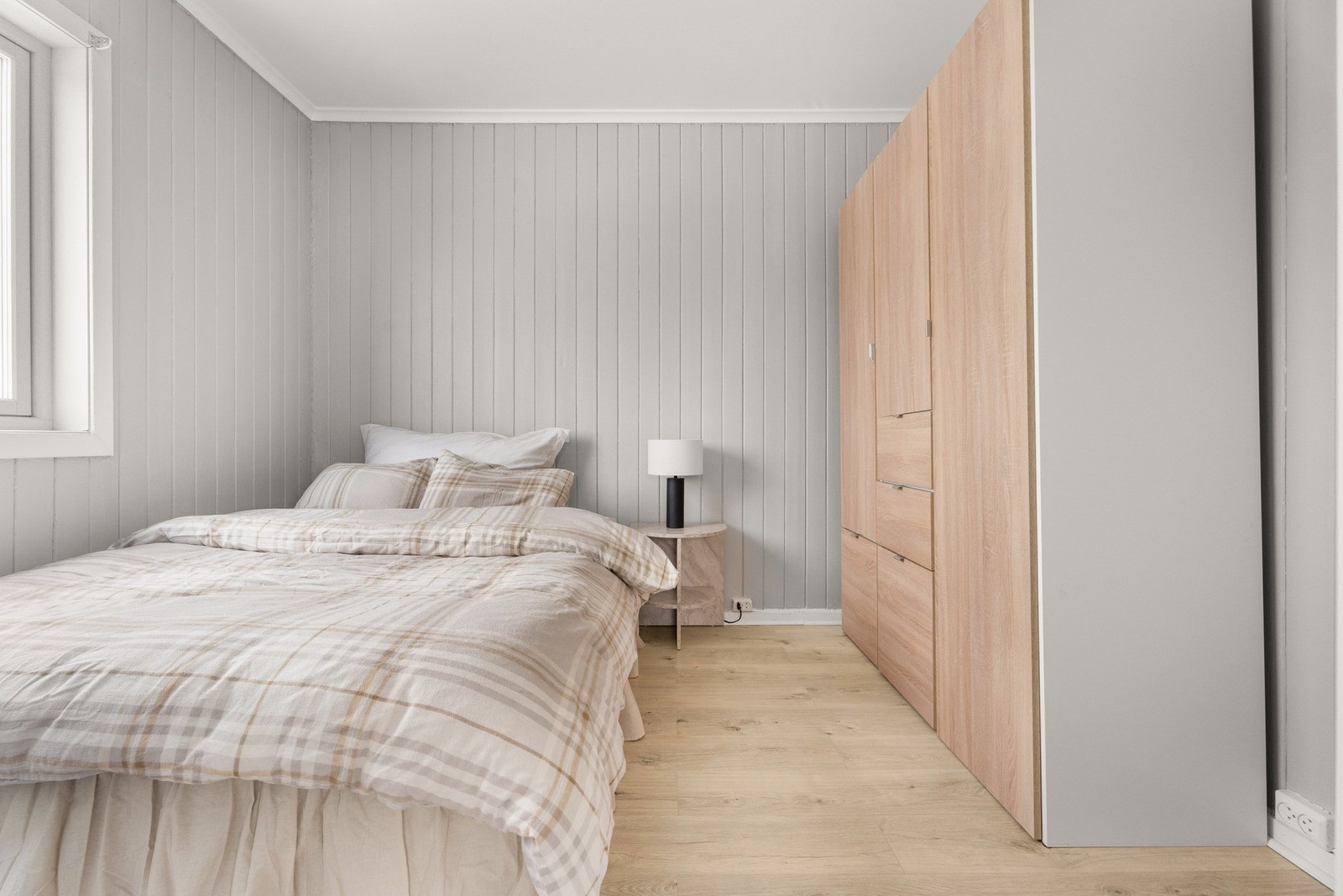 Leiligheten har et luftig og pent soverom med gråmalt panel på veggene og tidsmessig laminat på gulvet. Galleribilde