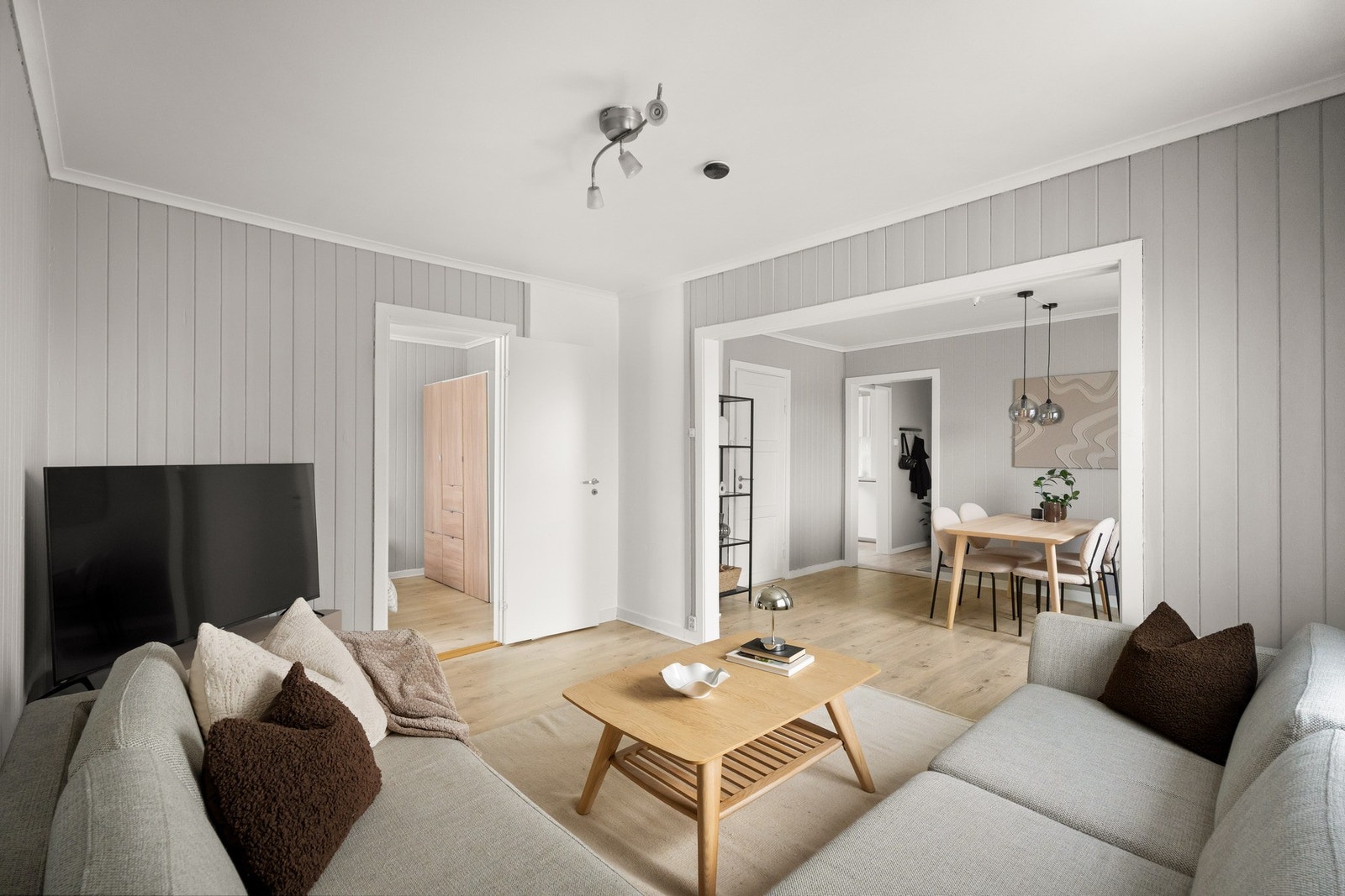 Stuen har gråmalt panel på veggene, to store vinduer og lys, enstavs laminat på gulvet. Galleribilde