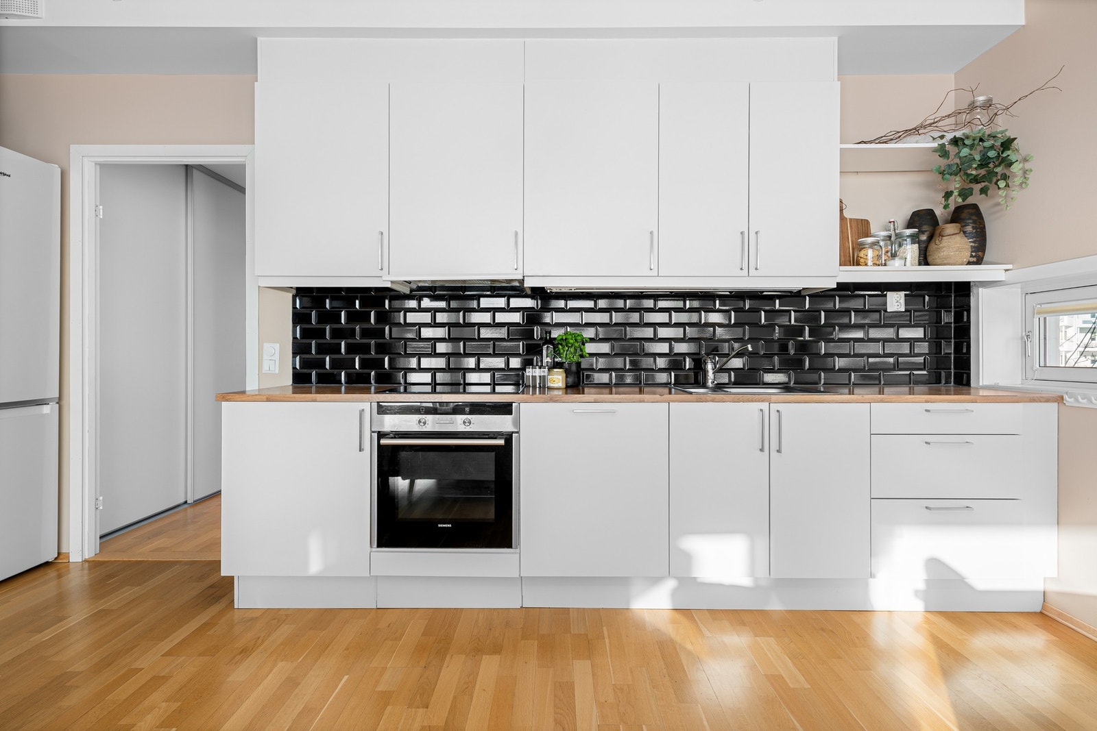 Lys og moderne kjøkkeninnredning fra 2011 med god skap- og benkeplass. Innredningen har hvite glatte fronter og benkeplate av treverk med nedfelt oppvaskkum. Galleribilde