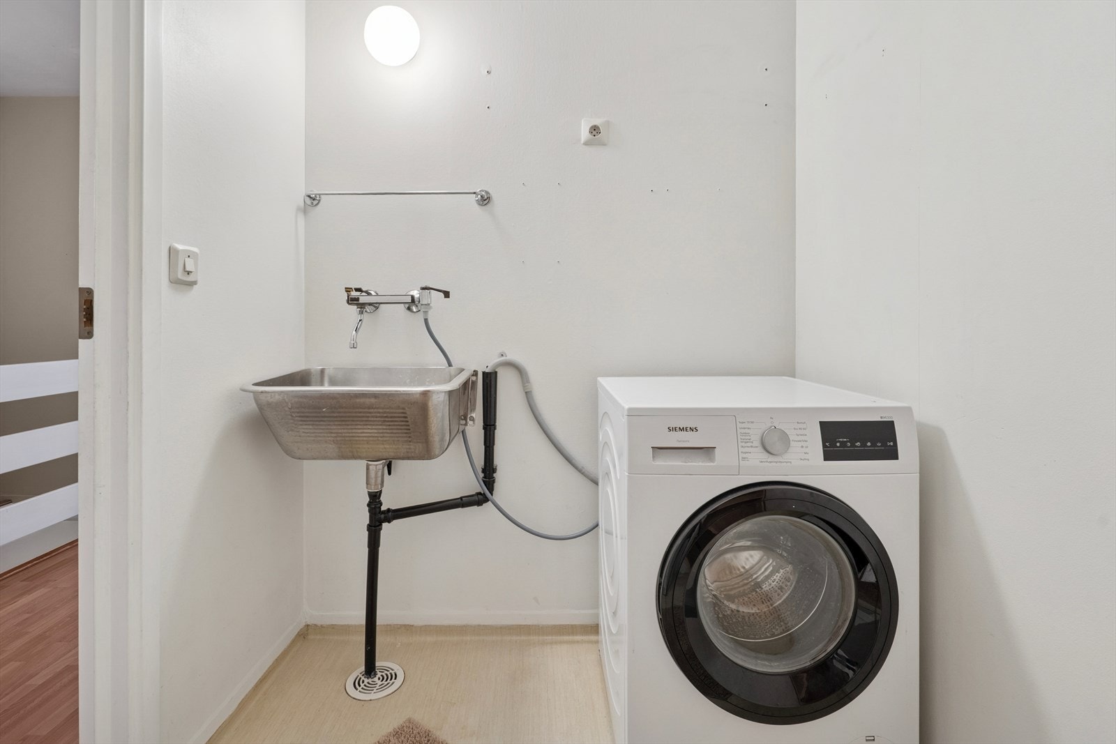 Vaskerom med opplegg for vaskemaskin samt utslagsvask på vegg. Galleribilde