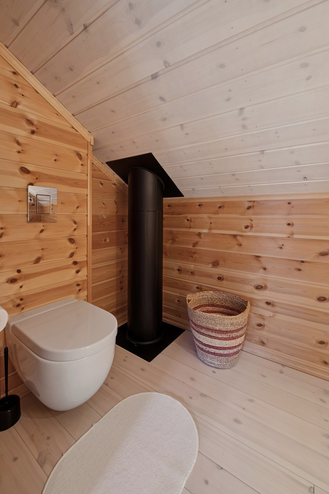 Toalettrom med servant og veggmontert toalett. Innredet med tregulv, panel på vegger og i himling - sjarmerende og funksjonelt. Galleribilde