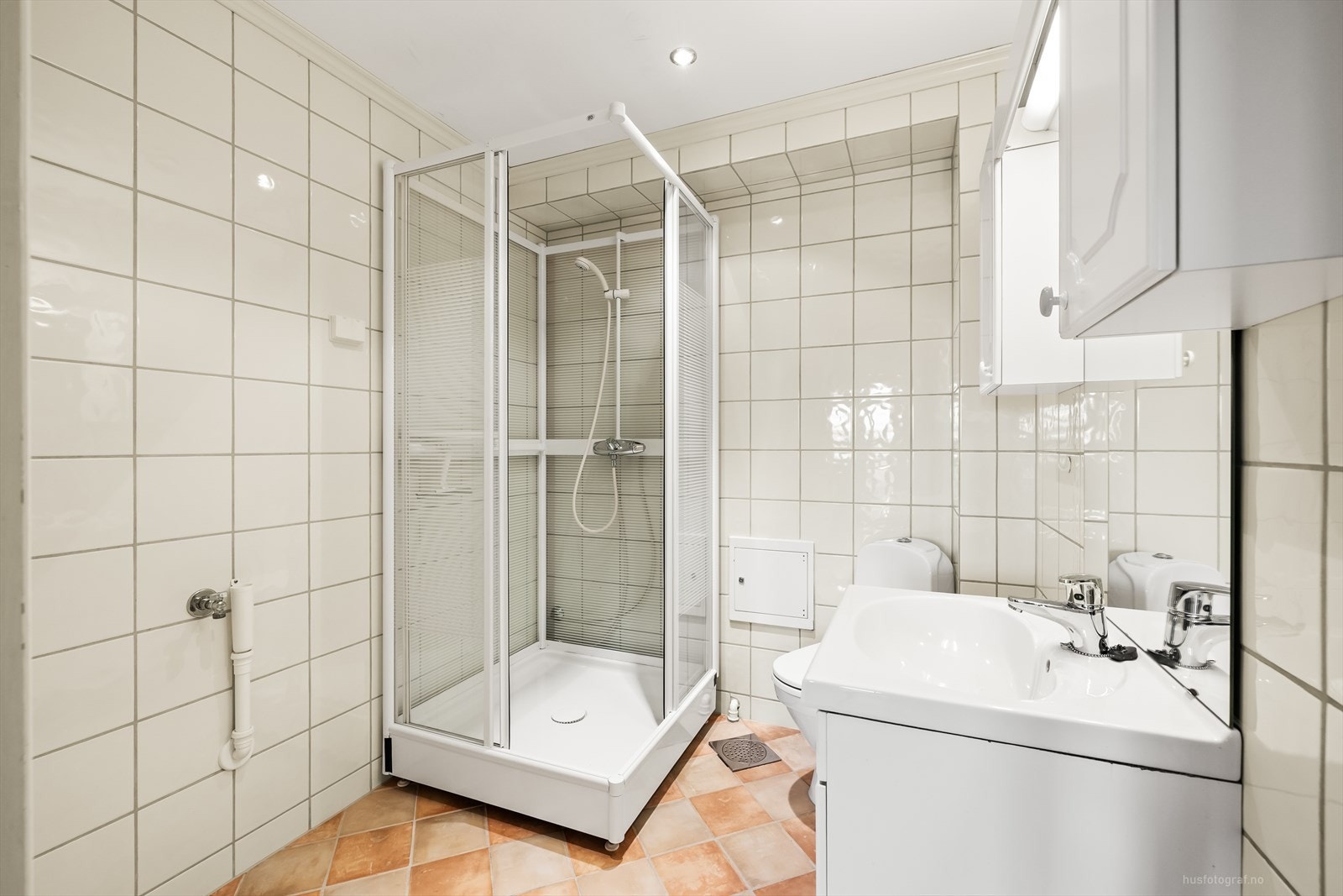 Pent flislagt bad i 1. etg. med varmekabler i gulv, klosett, baderomsinnredning med servant, dusjkabinett og opplegg til vaskemaskin. Galleribilde