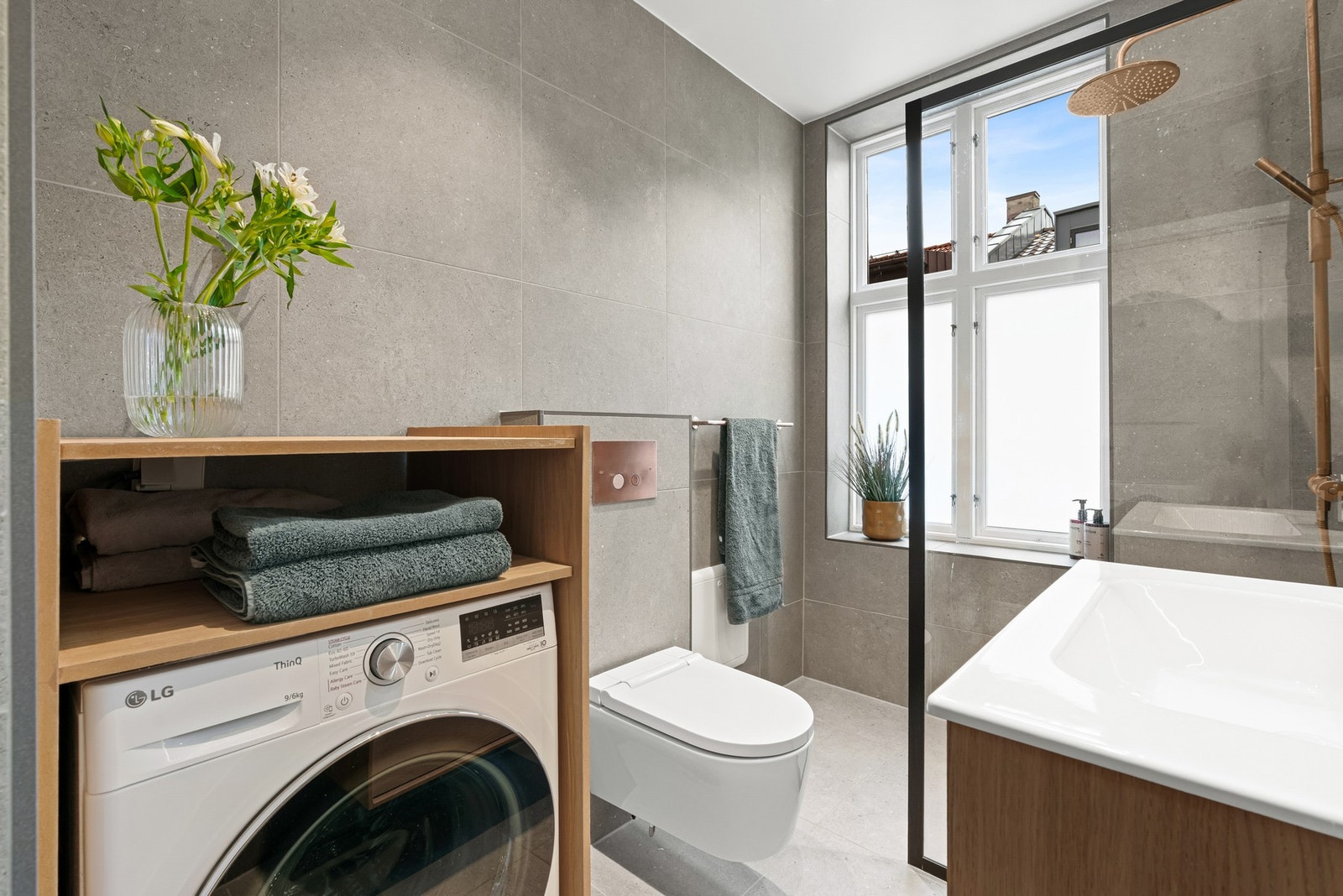 Badet har veggmontert toalett med spylefunksjon, varmekabler i gulv, downlights i tak og opplegg for vaskemaskin Galleribilde