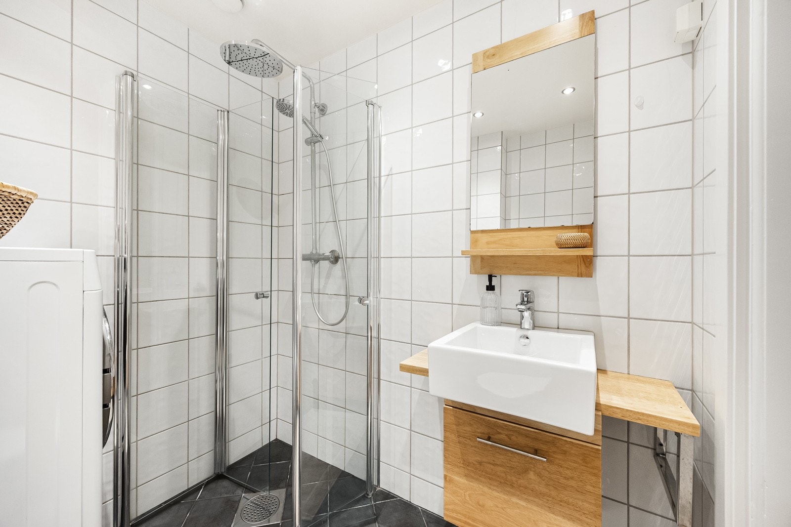 Badet har dusjhjørne med svingbare dusjvegger og termostatstyrt dusjbatteri i krom med både hånddusj og regnfallsdusj. Galleribilde