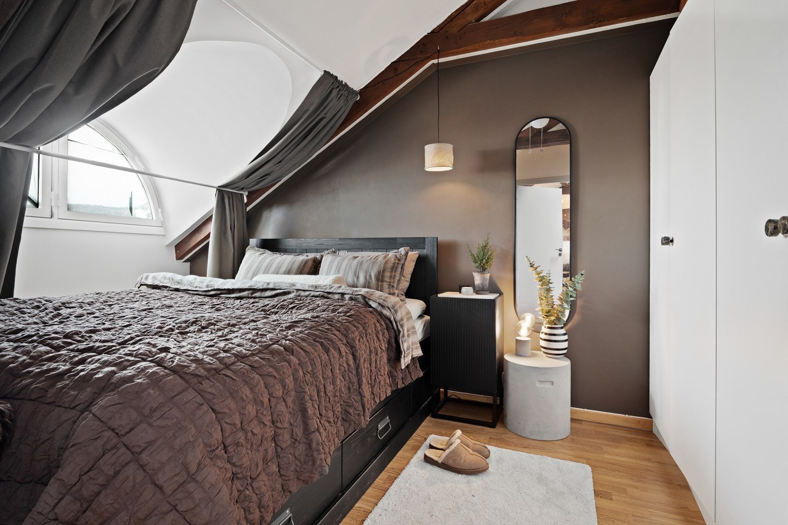 Soverommet har malte overflater i hvitt og brunt, laminatgulv, sjarmerende tredragere og buet vindu uten innsyn. Galleribilde