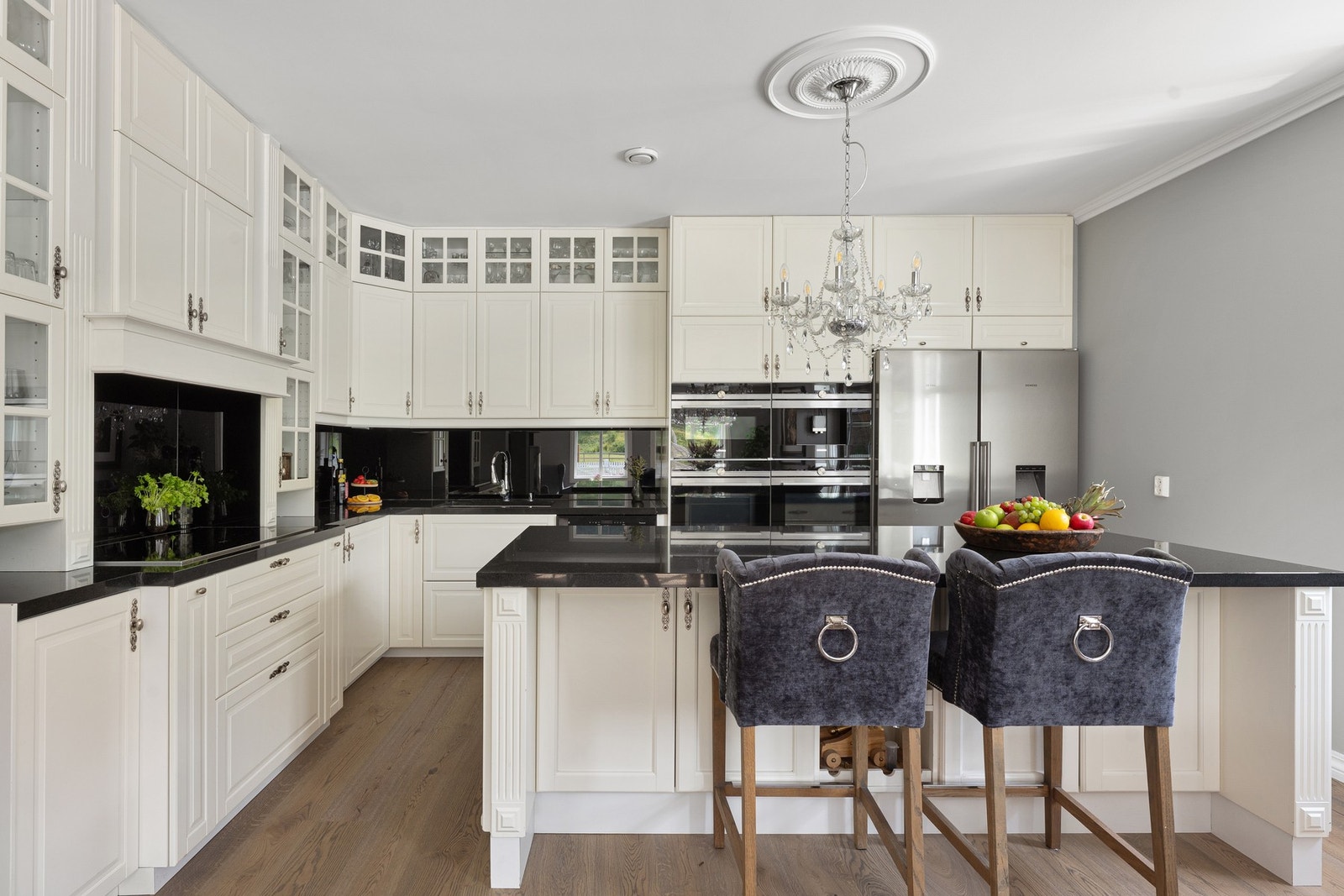 Stort og moderne kjøkken med profilerte fronter og benkeplate i stein. Galleribilde