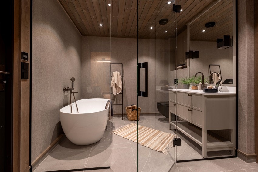 Rommet har flislagte gulv med vannbåren gulvvarme og er innredet med servant og servantskap i behandlede finerte eikefronter, badekar og to separate dusjnisjer adskilt med herdet glassvegger/-dører Galleribilde