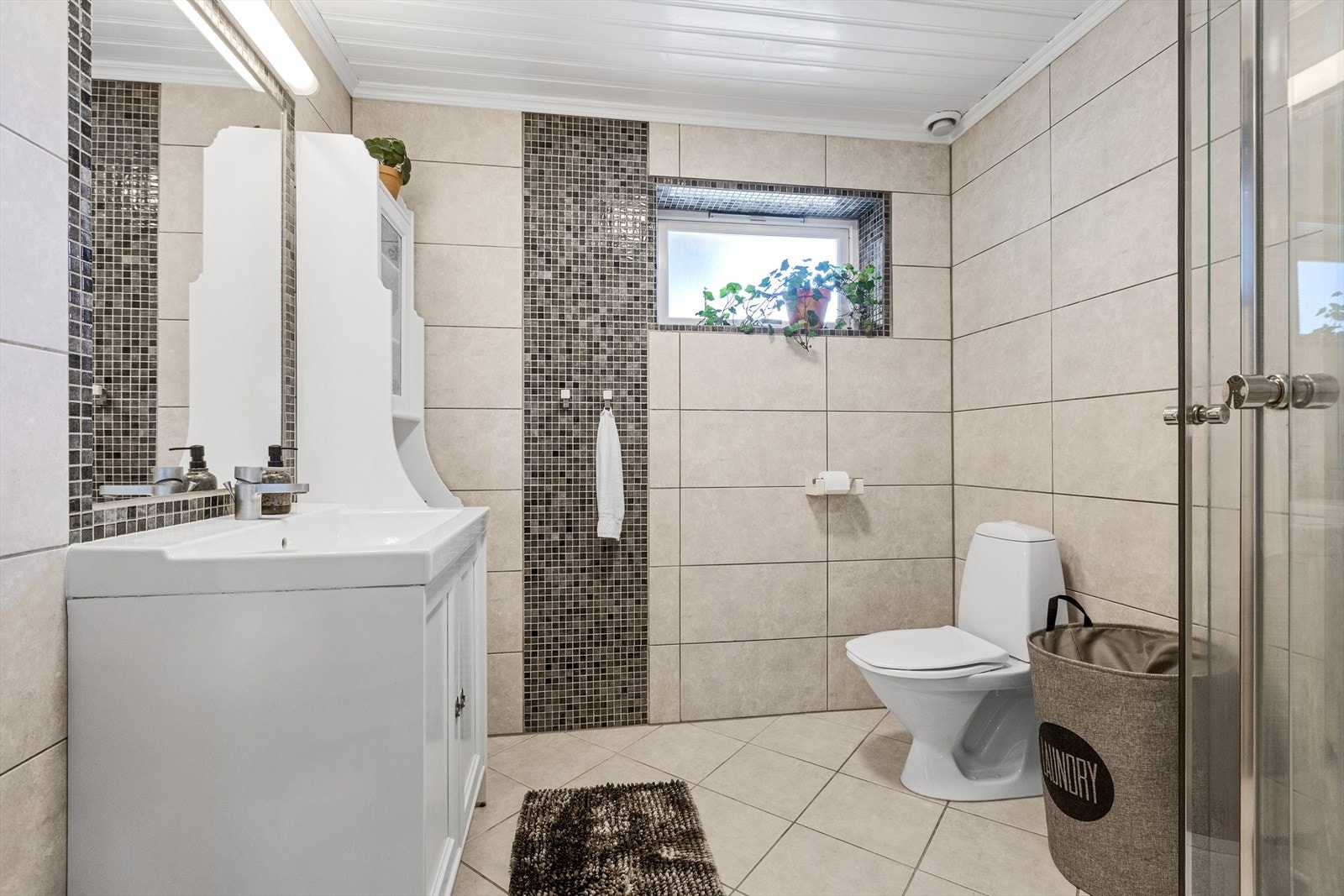 Delikat bad i underetasjen med dusjhjørne, toalett og servantinnredning. Galleribilde