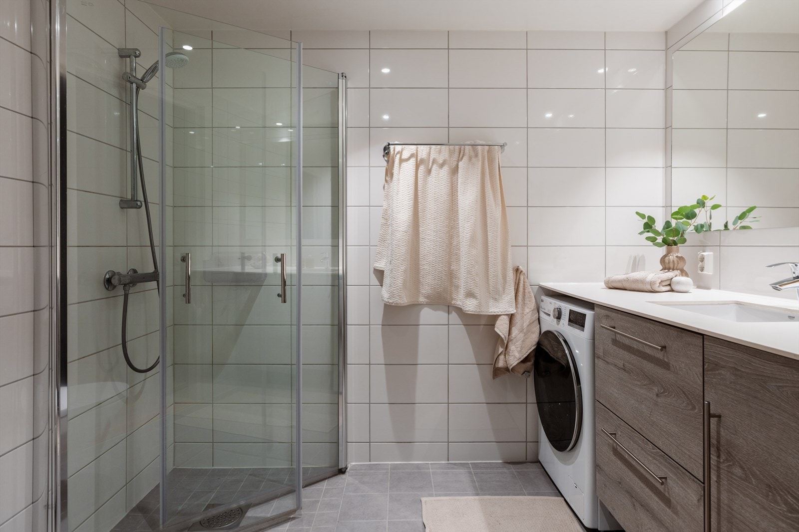 Flislagt baderom med nedsenket dusjnisje og innfellbare glassdører. Galleribilde