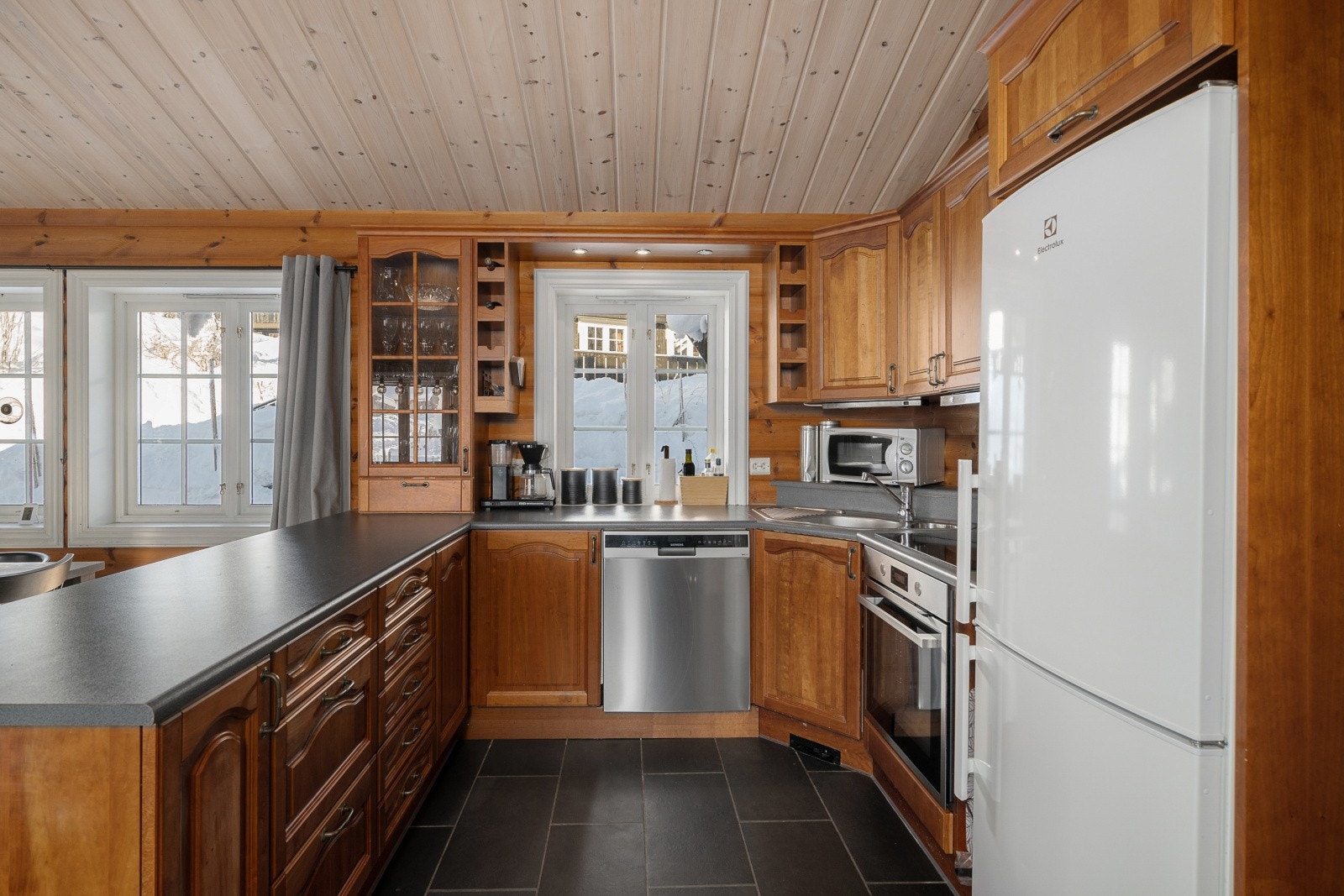 Kjøkkenet har en åpen løsning mot stuen og er utstyrt med en innredning med laminerte skrog, profilerte fronter og en laminert benkeplate. Galleribilde