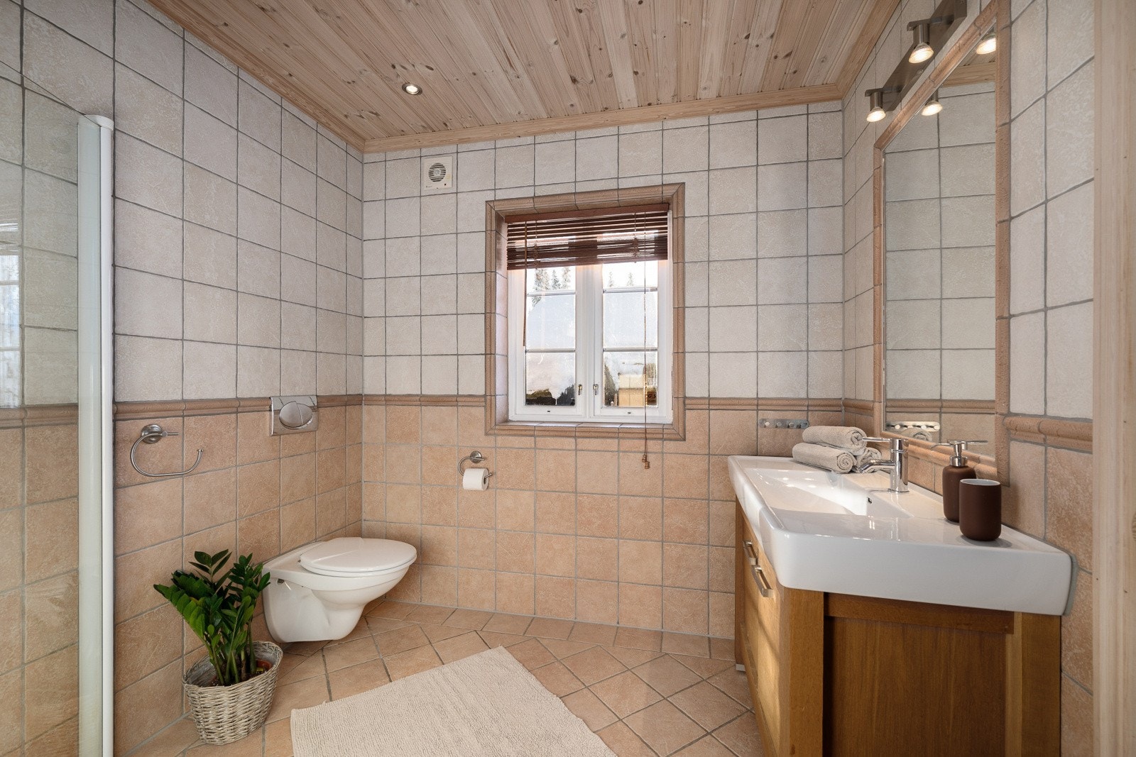 Badet er fra byggeår og har flislagte overflater på både gulv og vegger, med panel i himlingen. Galleribilde