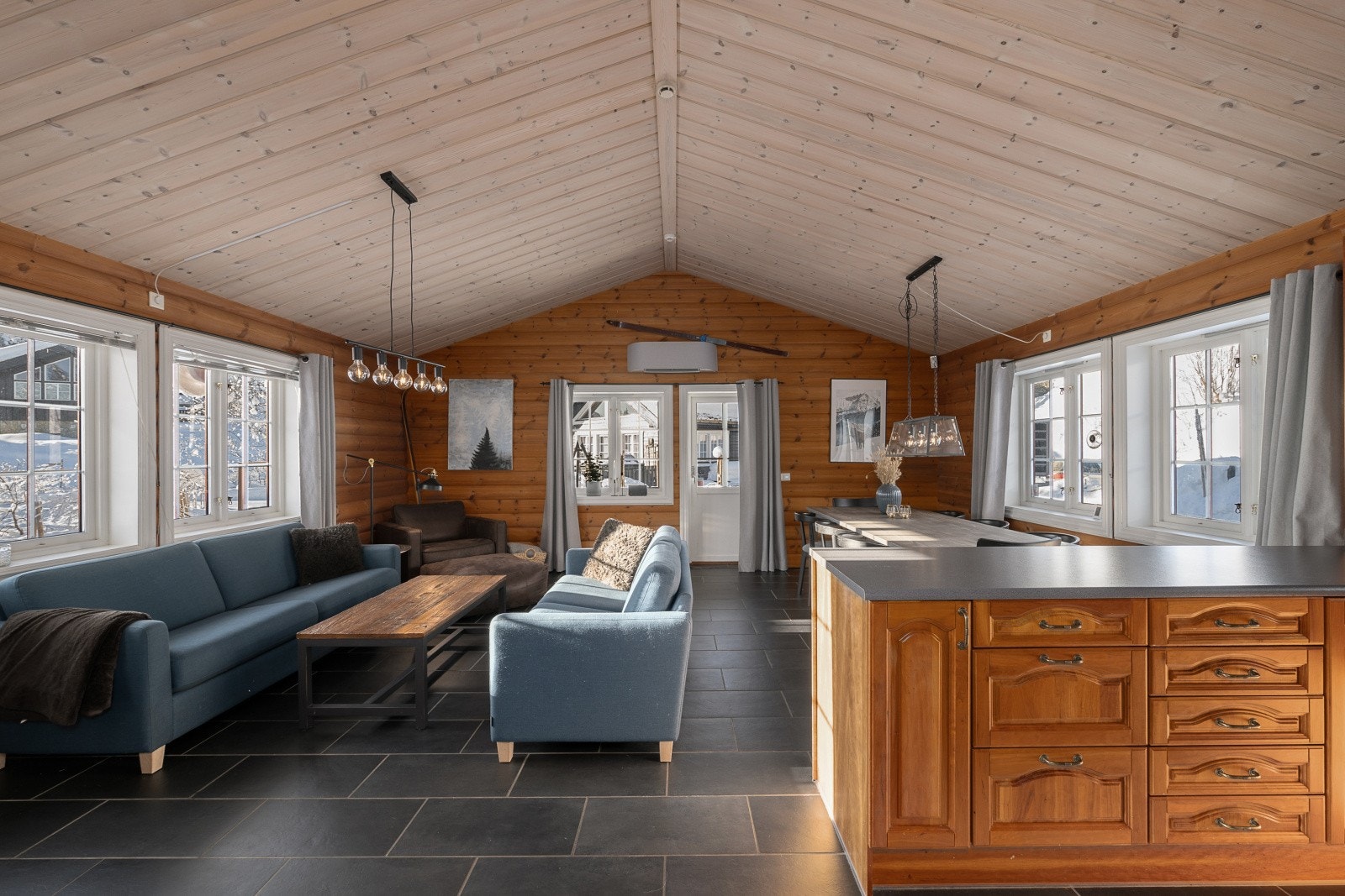 Stue og kjøkken i åpen løsning med god takhøyde og utgang til overbygget uteplass. Galleribilde