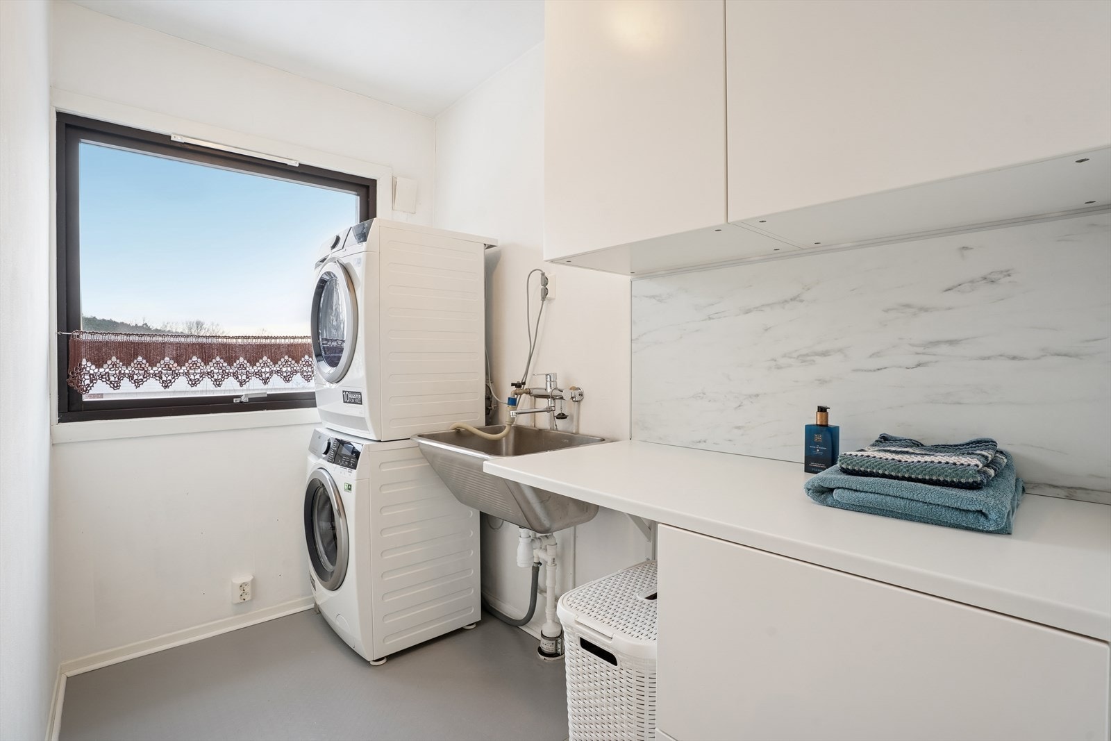 Vaskerommet har malte vegger og belegg på gulvet. Rommet er utstyrt med en praktisk skapinnredning med flere skap og en praktisk benkeplate Galleribilde