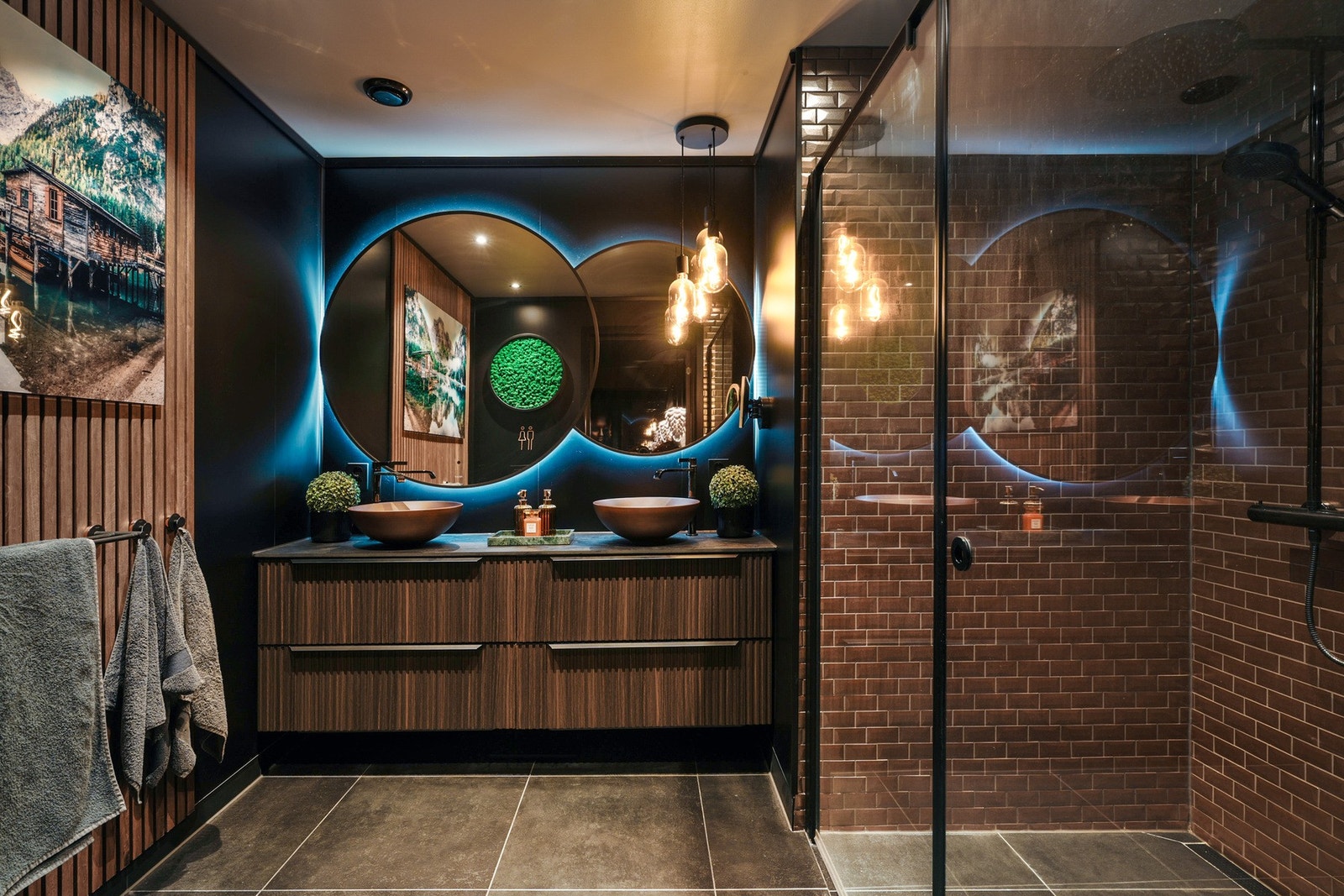 Den mørke og dempede stilen går igjen også i baderomsinnredningen fra Scala. Dusjen er lagt med flis i kobberfarge, og lyset bak speilet kan dimmes. Galleribilde