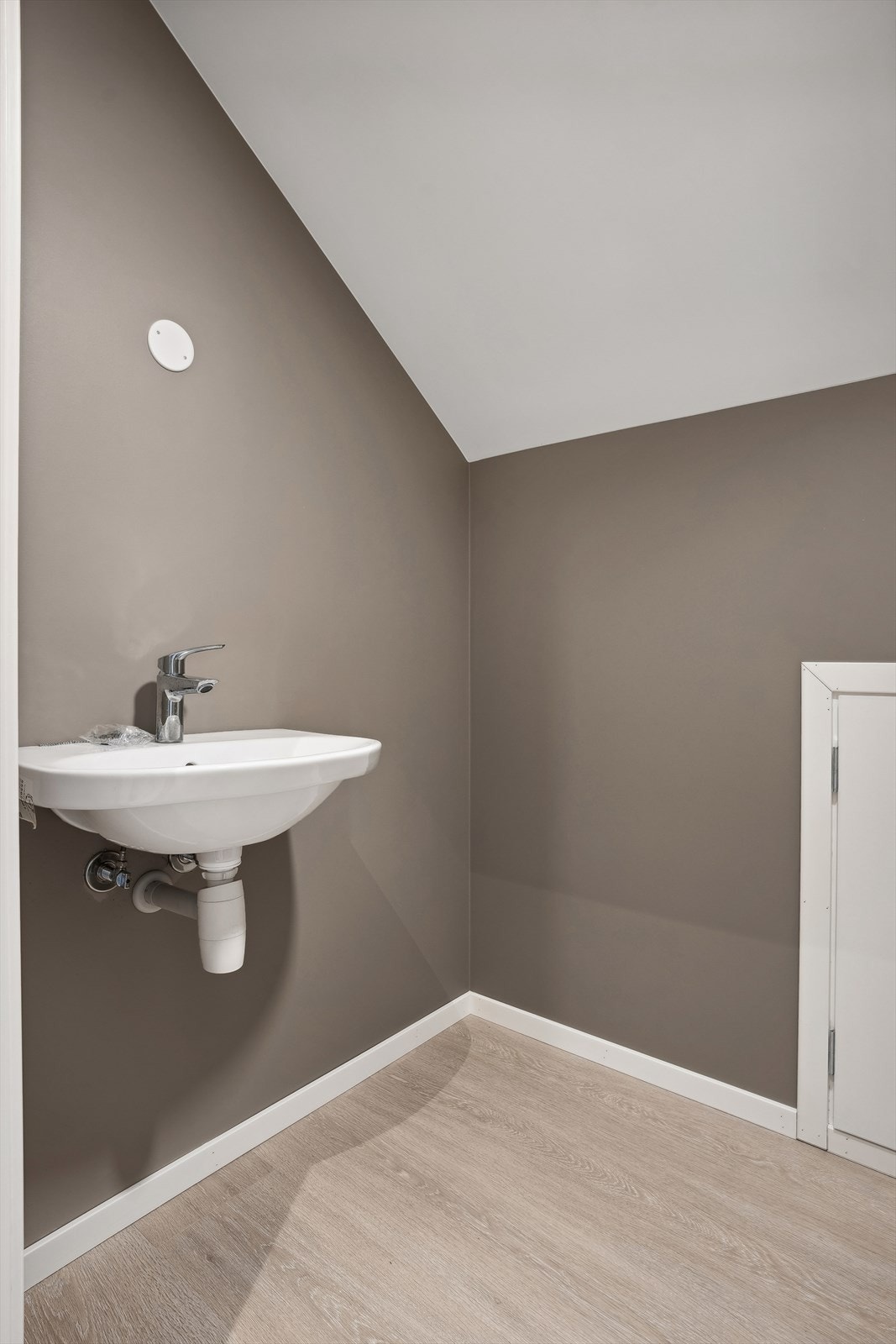 Toalett rommet er enkelt innredet med toalett og servant på vegg. Galleribilde