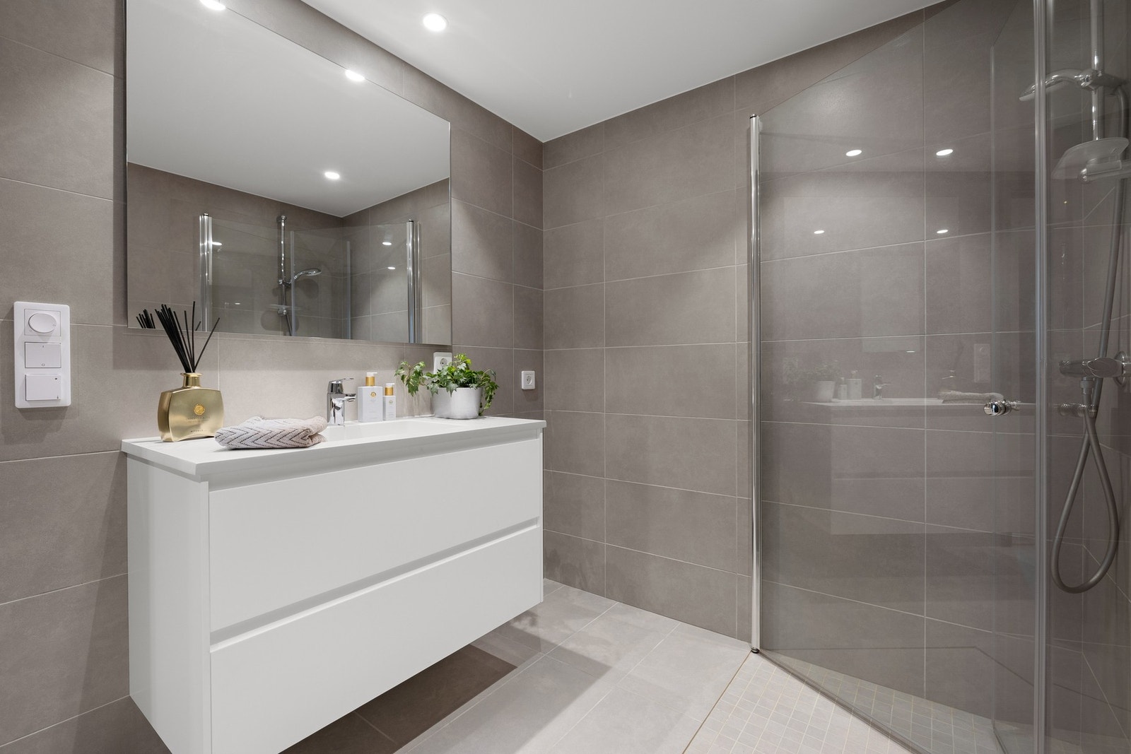 Badet er på ca. 5,5 kvm og er utstyrt med vegghengt WC, moderne innredning og dusjhjørne med innfellbare dører. Galleribilde