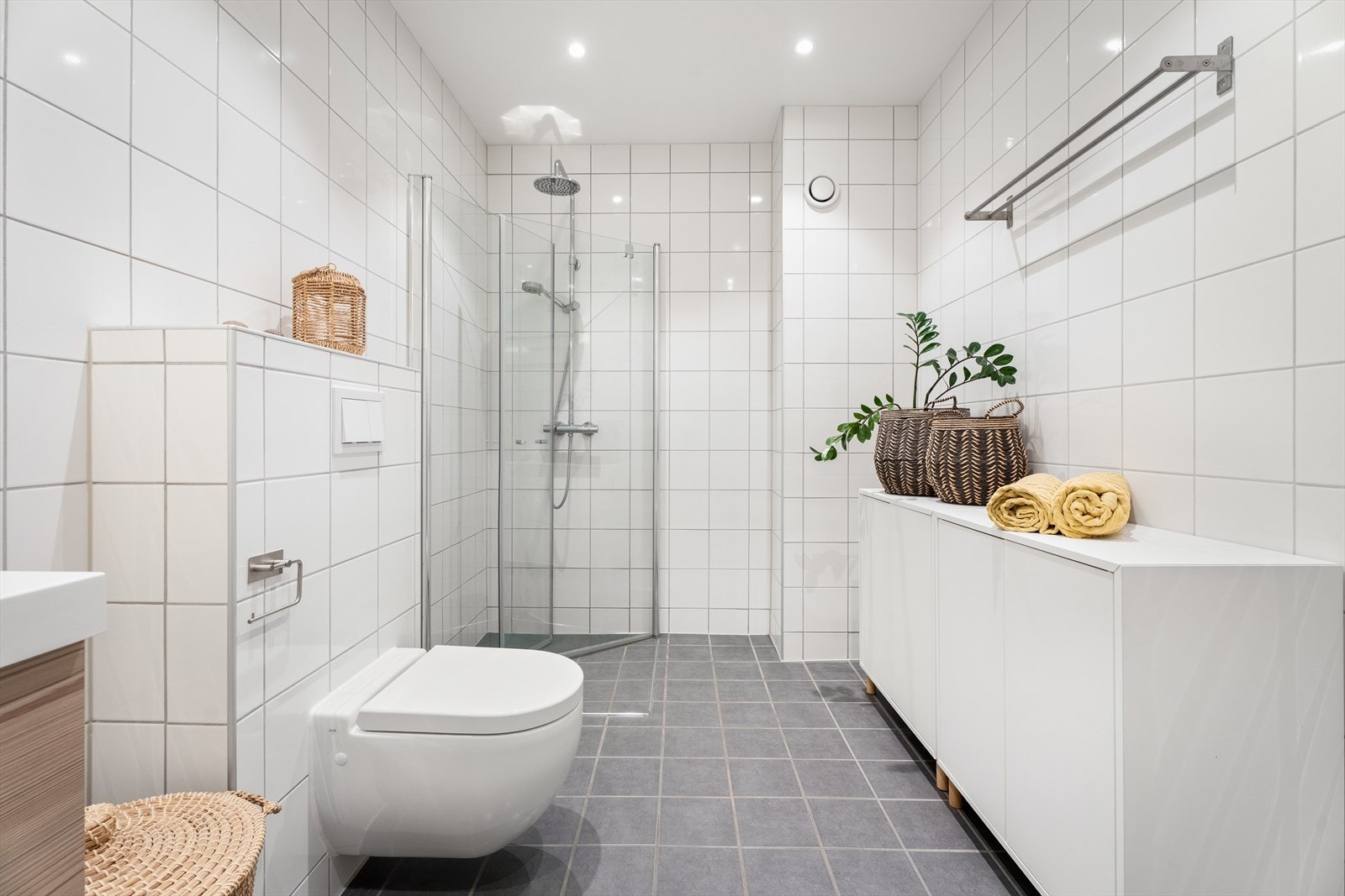 Dusjhjørne med glassdører og vegghengt toalett gir effektiv bruk av rommet. Galleribilde