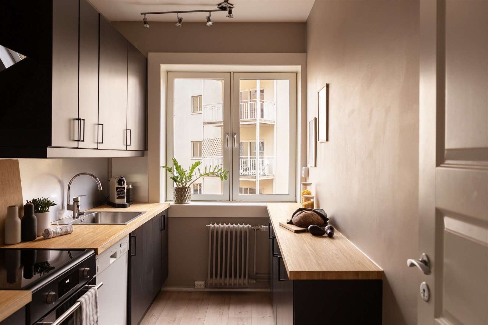 IKEA kjøkkeninnredning bestående av bl.a. heltre benkeplate, frittstående komfyr, kjøle-/fryseskap og oppvaskmaskin i nisje Galleribilde