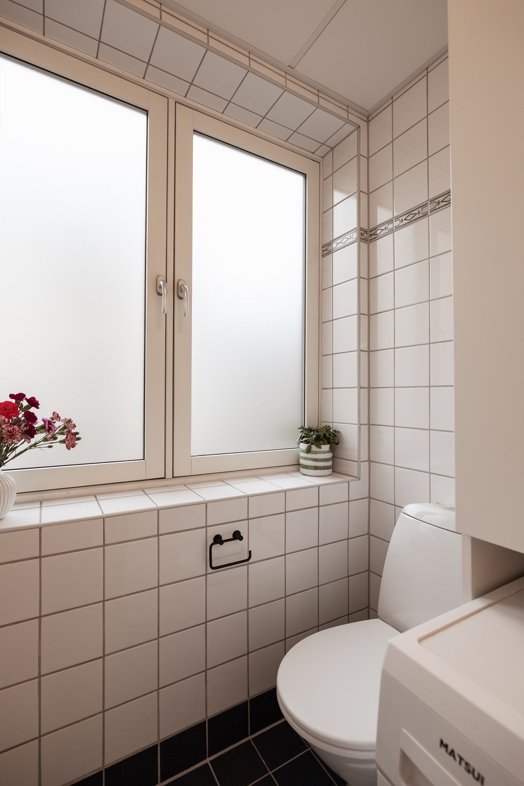 Innerst på badet er det gulvstående toalett og opplegg for vaskemaskin Galleribilde