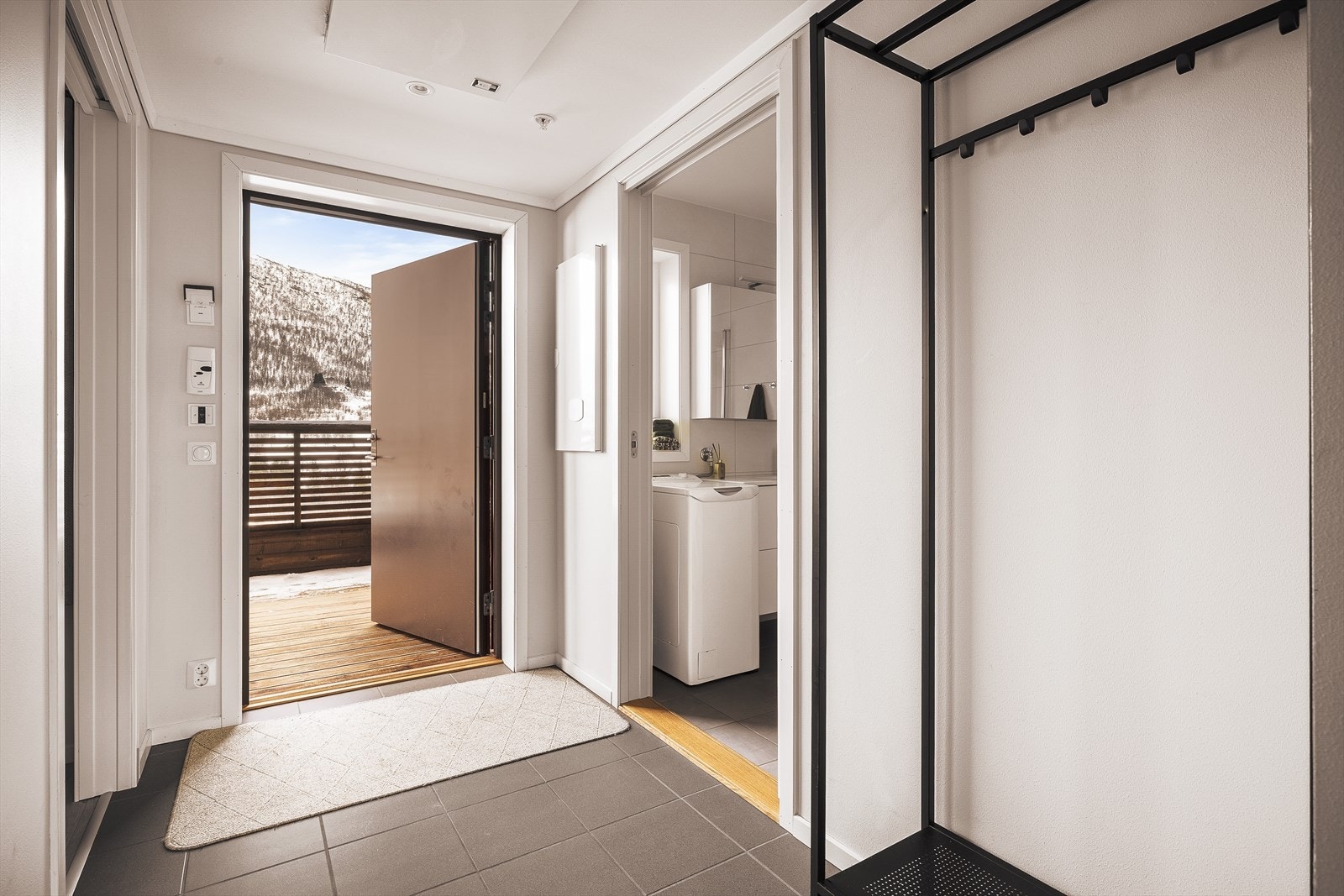 Praktisk entré med flislagt gulv og gipsvegger i lyse, rene flater Galleribilde