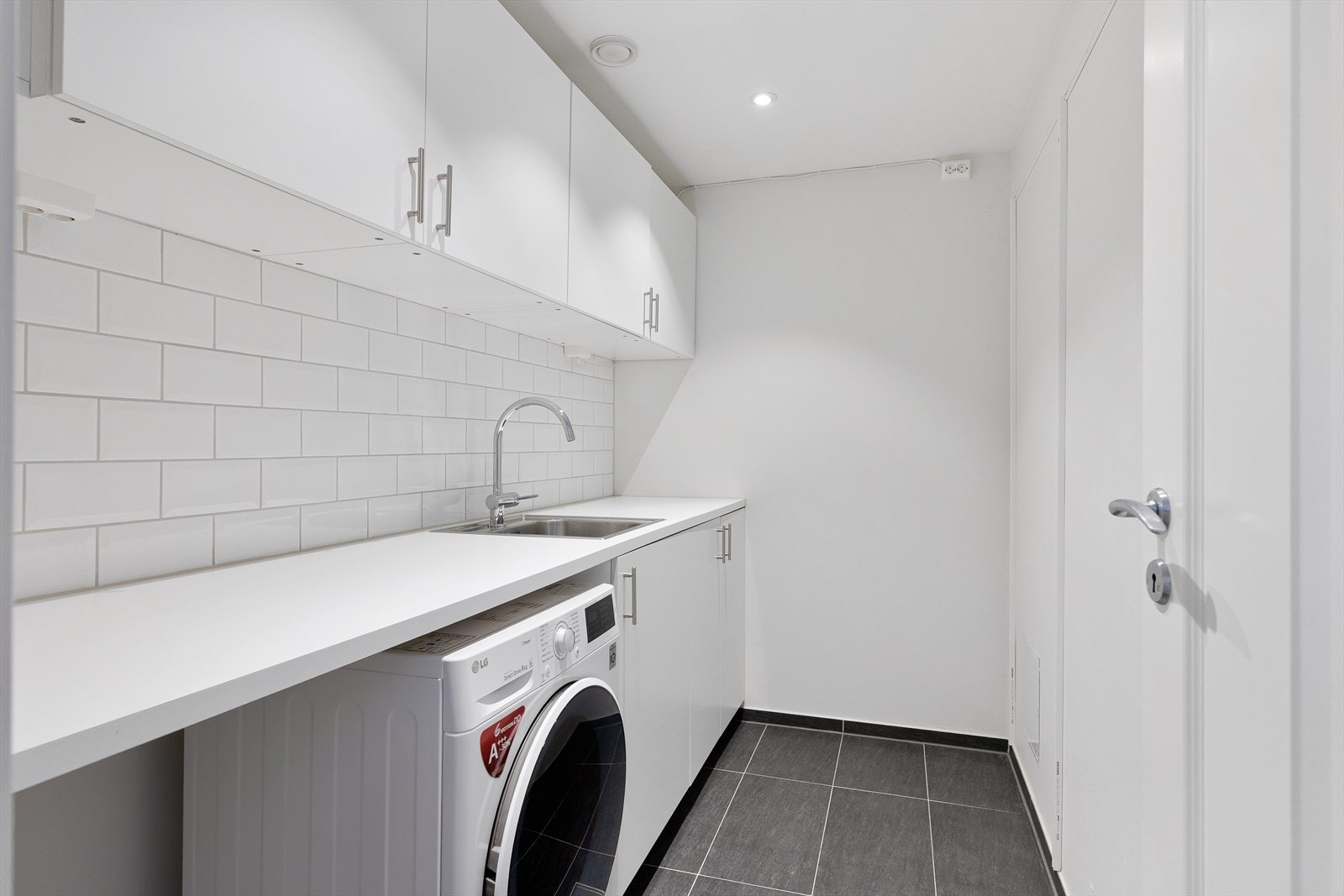 Separat og praktisk vaskerom med opplegg for vaskemaskin og god benkeplass. Galleribilde