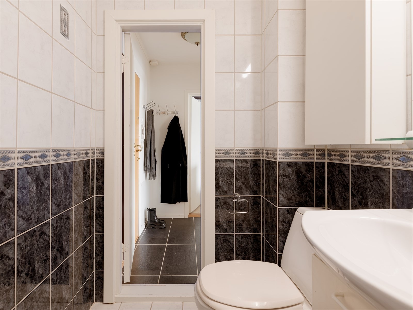 Baderomsinnredning med glatte, folierte fronter og heldekkende servant. Det er speil med lysarmatur over servantinnredningen. Galleribilde