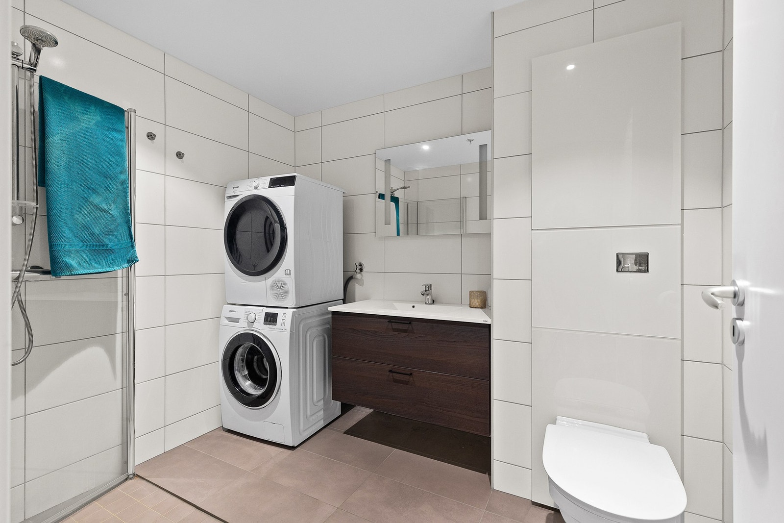 Romslig baderom med flislagte overflater, lun gulvvarme og opplegg for både vaskemaskin og tørketrommel. Galleribilde