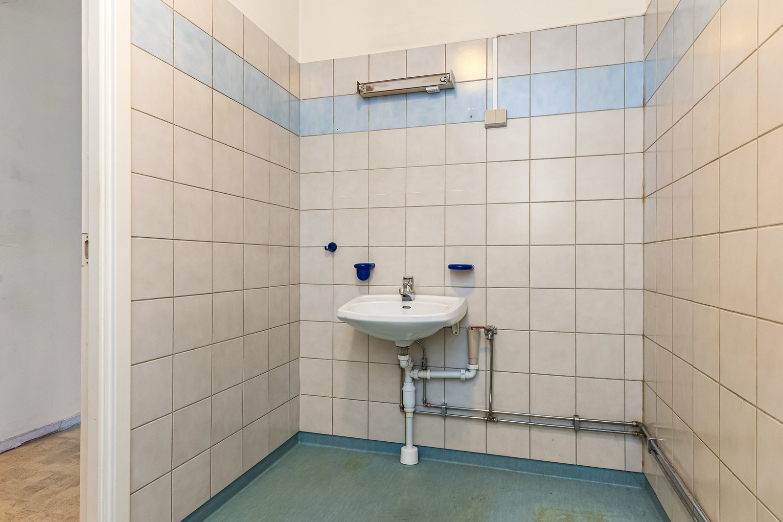 Baderommet har fliser på veggene og vinylbelegg på gulvet med praktisk oppbrett. Galleribilde