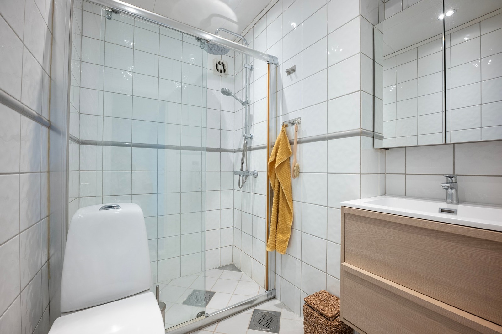 Leiligheten har et flislagt bad med gulvvarme. Badet er utstyrt med toalett, dusjhjørne, ny servant med to skuffefronter, og speilskap. Galleribilde