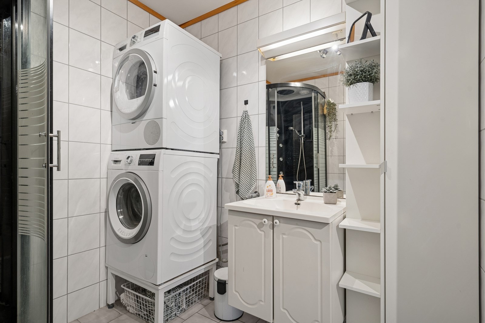 Badet er utstyrt med dusjkabinett, toalett, servant og opplegg til vaskemaskin og tørketrommel Galleribilde