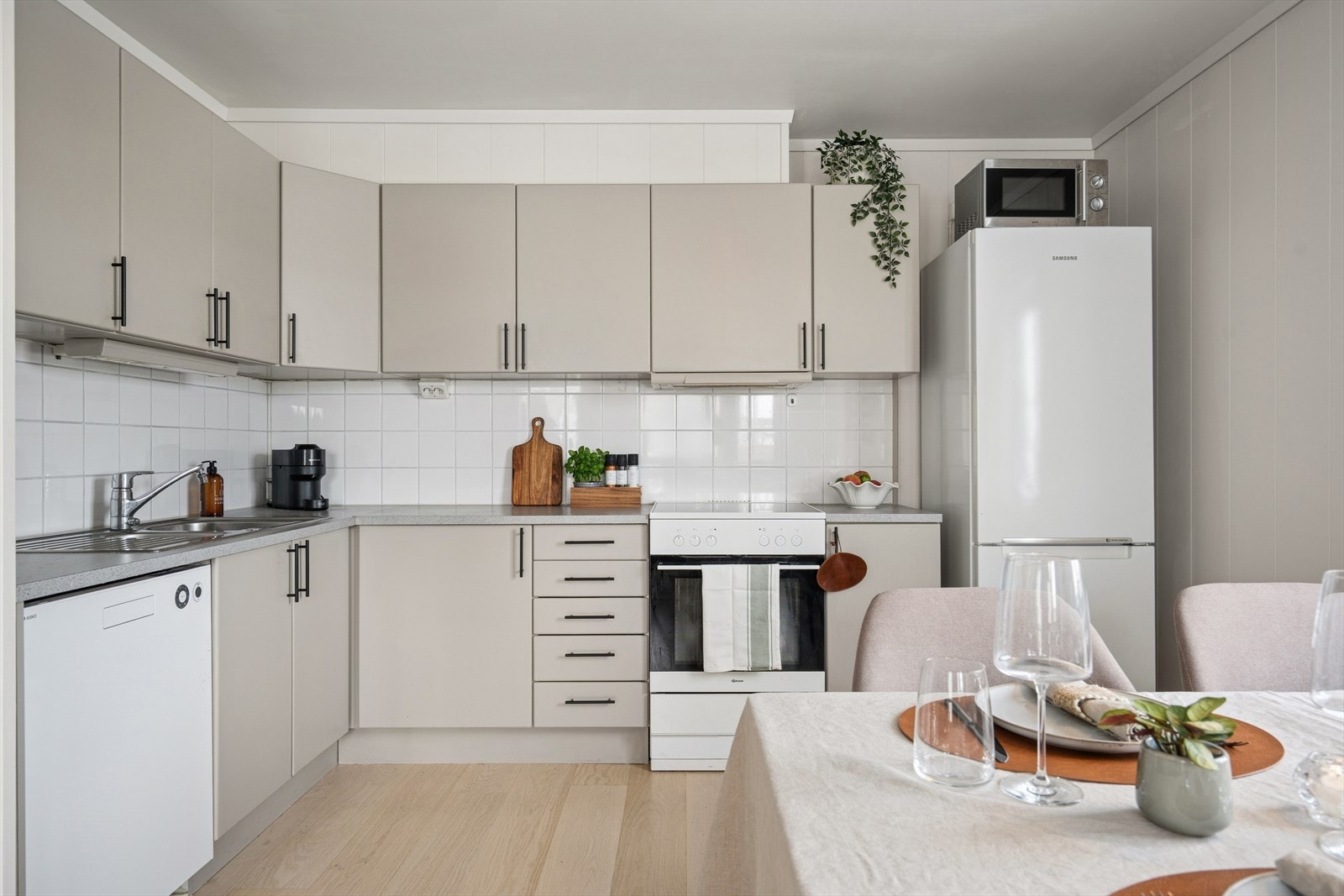 Kjøkkenet med slette fronter, godt utnyttet med skap og benkeplass. Hvite fliser over kjøkkenbenken Galleribilde