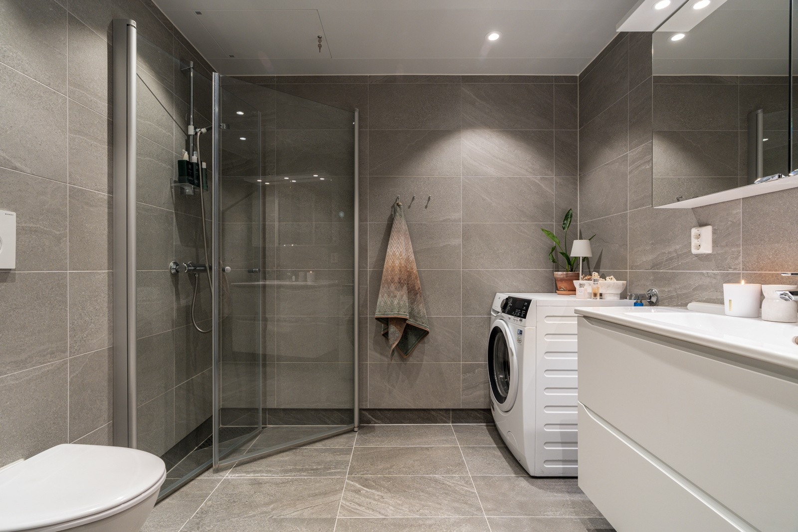 Delikat, flislagt bad med gulvvarme, stort dusjhjørne og praktisk vegghengt toalett.