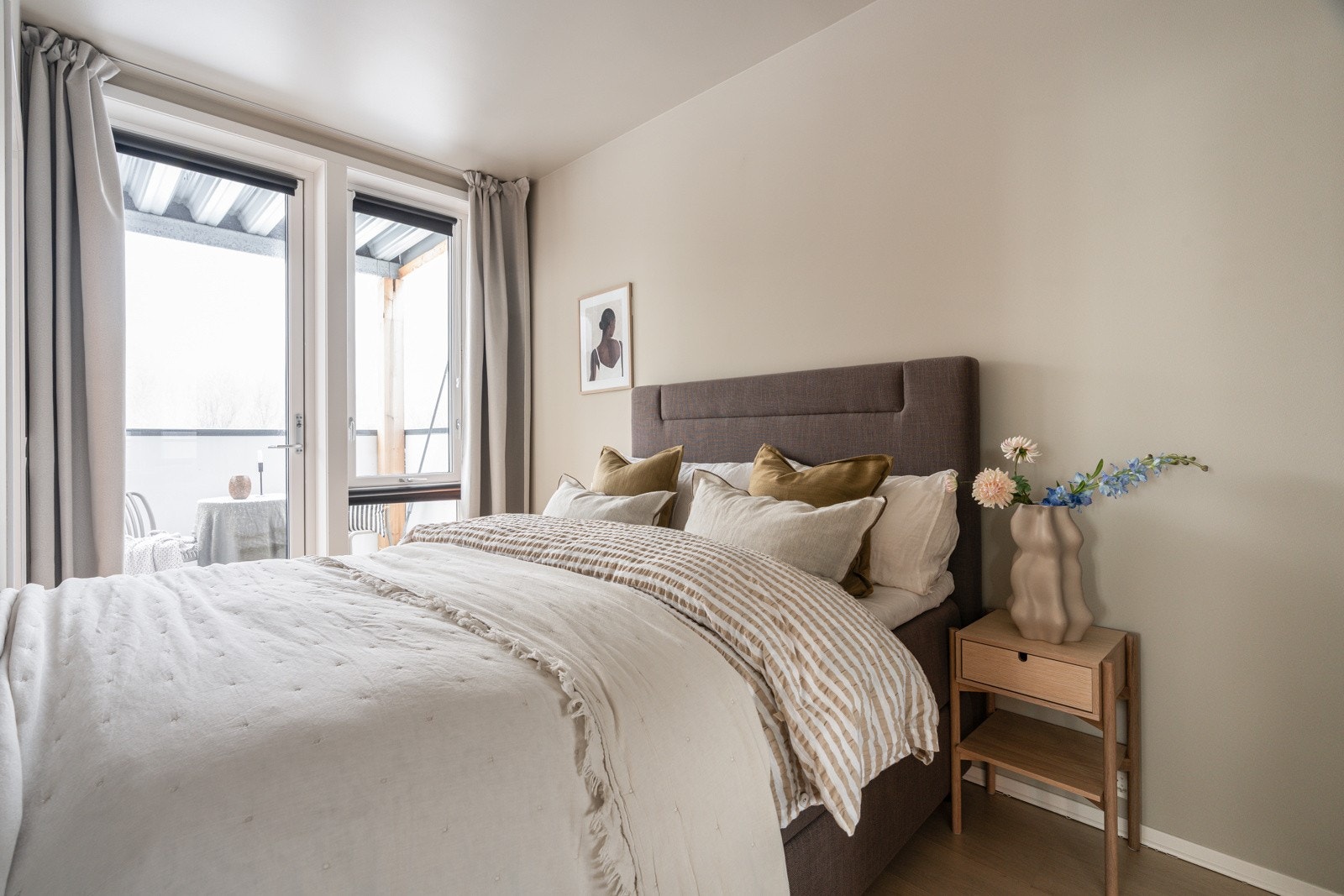 God plass til stor seng med tilhørende nattbord. Her har man utgang til leilighetens andre balkong.