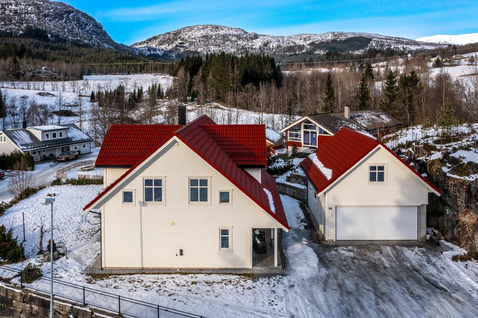 Eiendommen er på 1 254 kvm og inneholder enebolig og en frittliggende garasje som går over to plan. Her er det mange parkeringsmuligheter. Tomten er pent opparbeidet med romslig asfaltert tun/parkeringsplass. Galleribilde