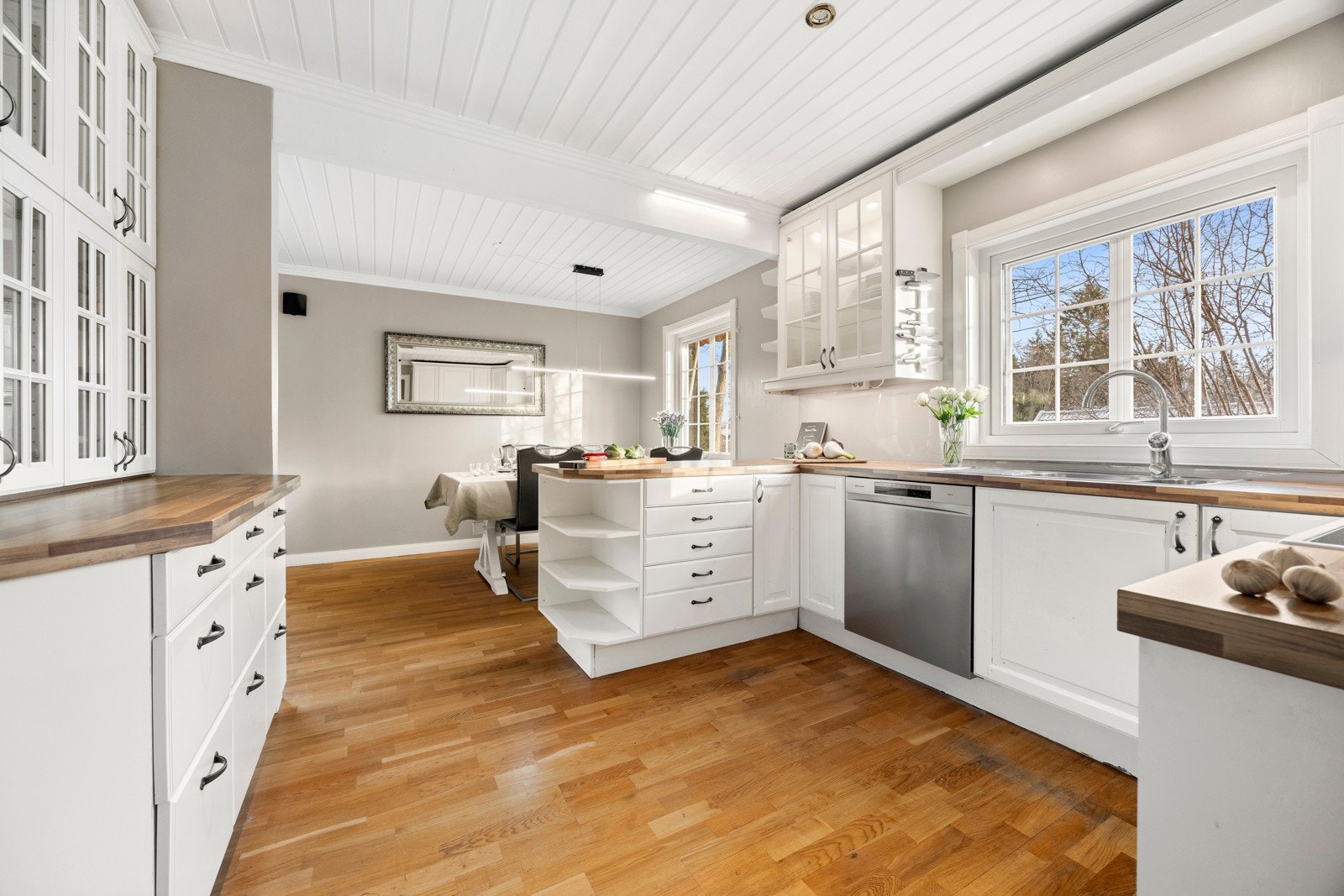 Kjøkkeninnredning med profilerte og malte fronter, samt fronter med glass, laminat benk, nedfelt kum med benkebeslag og ventilator Galleribilde