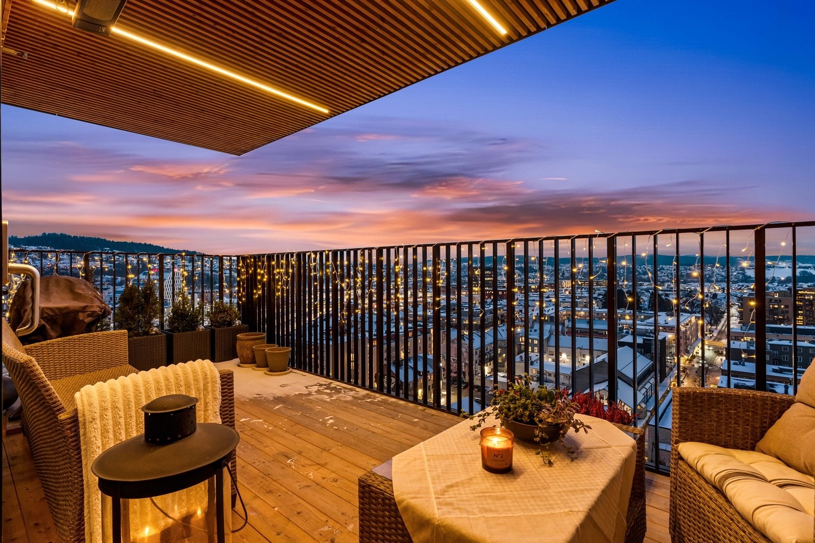 Terrassen har tregulv og stålrekkverk, med flott utsikt over bylandskapet. Galleribilde