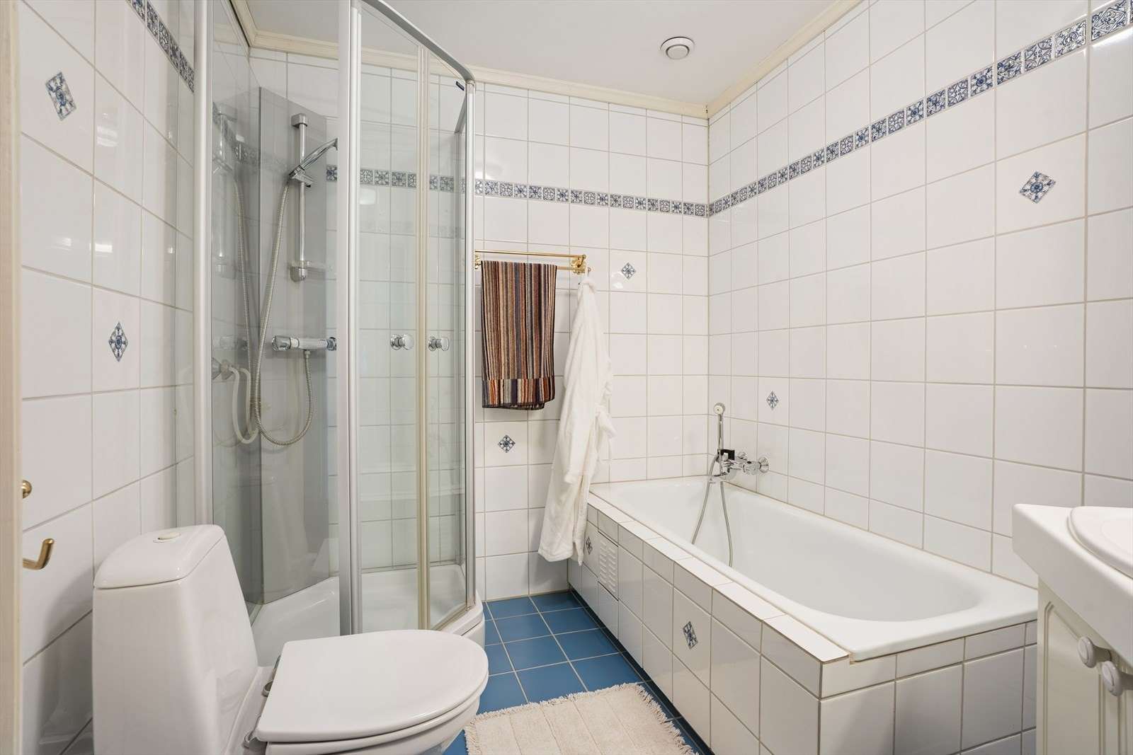 Badet er utstyrt med servantinnredning, speil, dusjkabinett, badekar og gulvmontert toalett Galleribilde