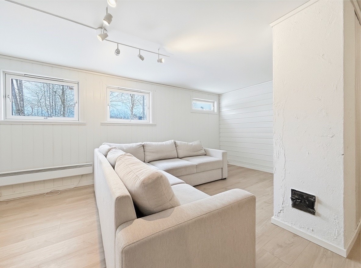 Stuen har sofa og store vinduer som slipper inn godt med dagslys Galleribilde