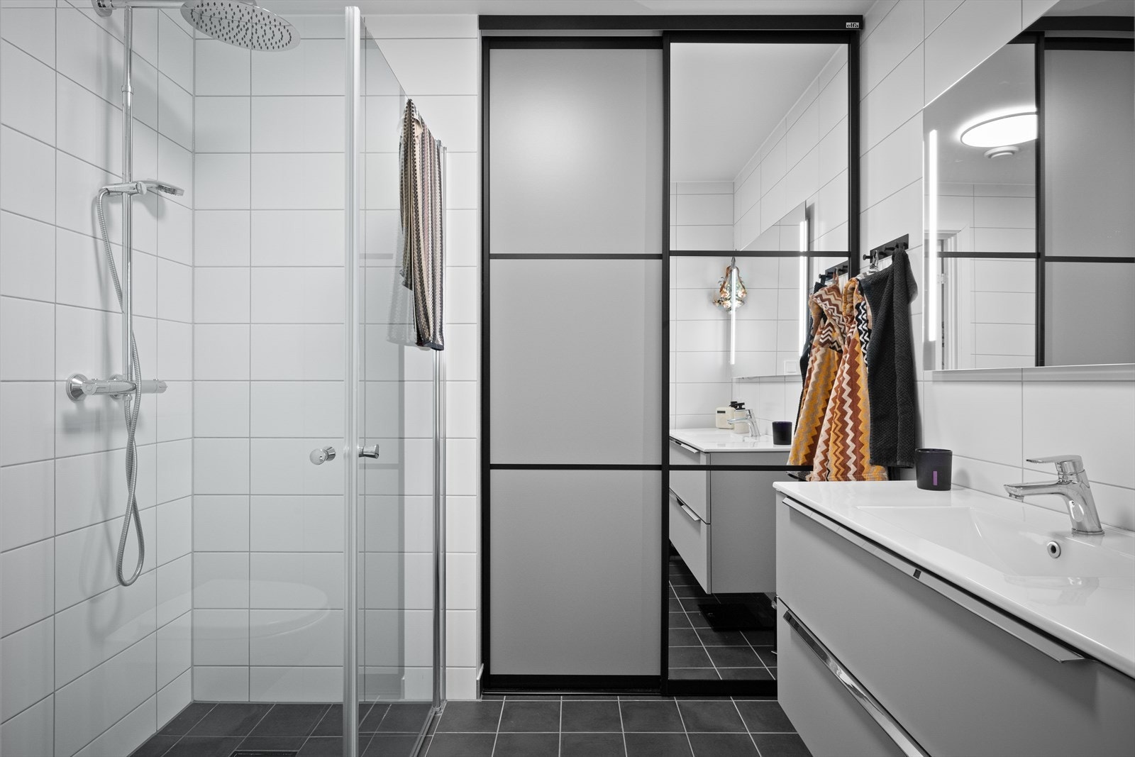 Flislagt baderom med opplegg for vaskemaskin, vegghengt toalett og baderomsinnredning Galleribilde