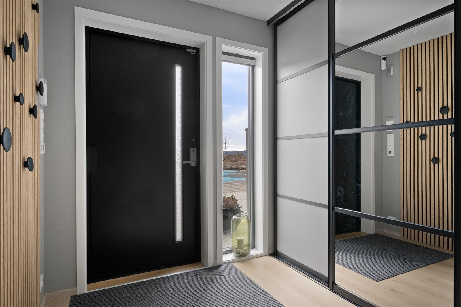 Velkommen inn! Moderne inngang med stilrent design og vindusflater som slipper inn rikelig med naturlig lys. Skyvedørsgarderobe med god plass til yttertøy Galleribilde
