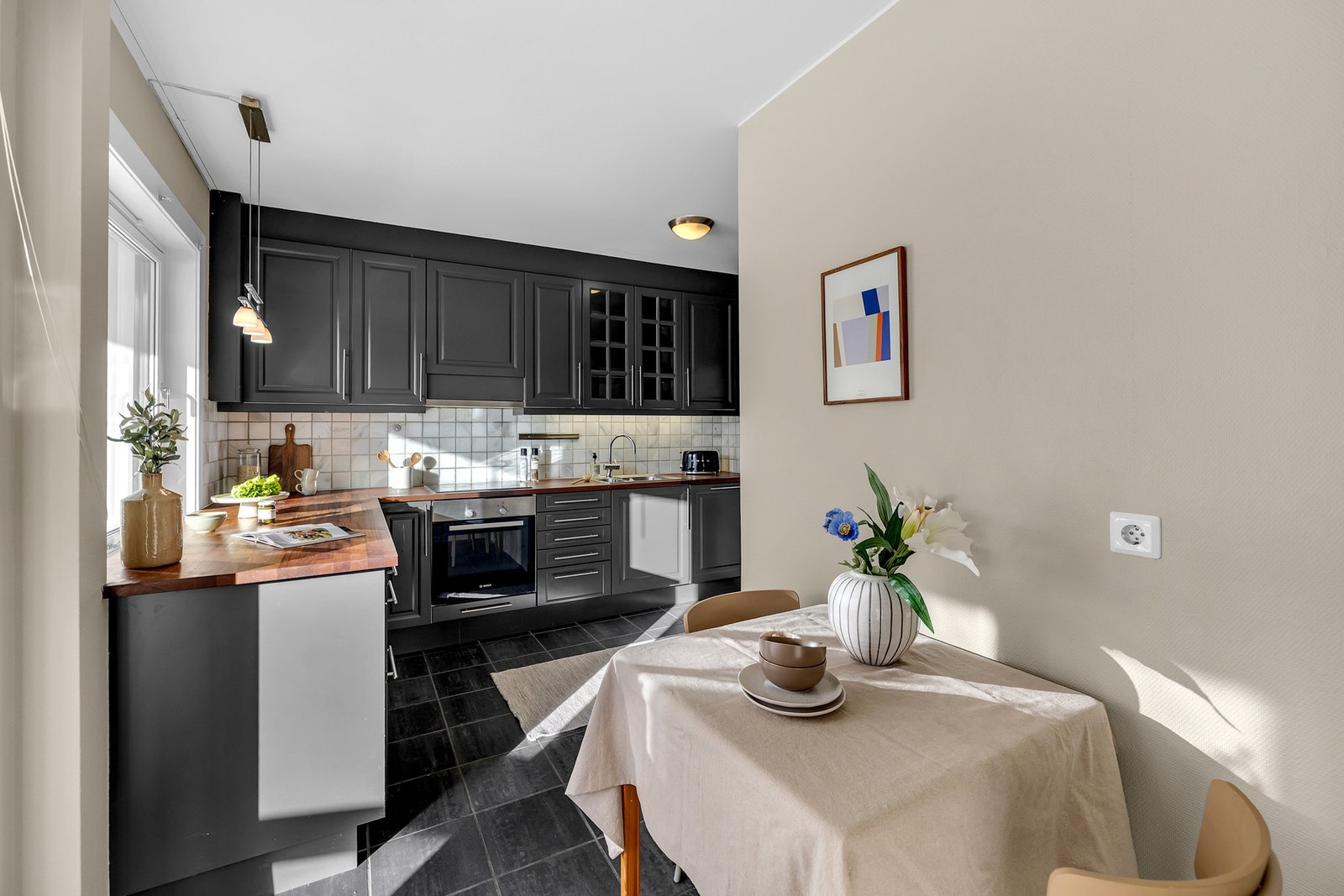 Det er flislagt mellom benkeplate og overskap, samt belysning og stikkontakter under overskap. Galleribilde