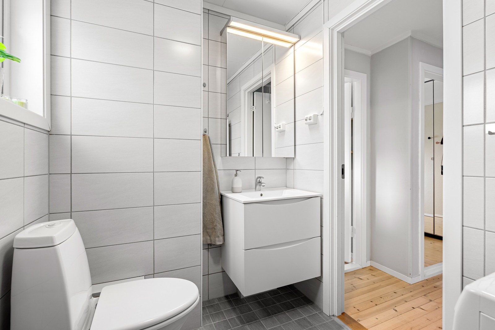 Flislagt bad med dusjhjørne og opplegg til vaskemaskin Galleribilde