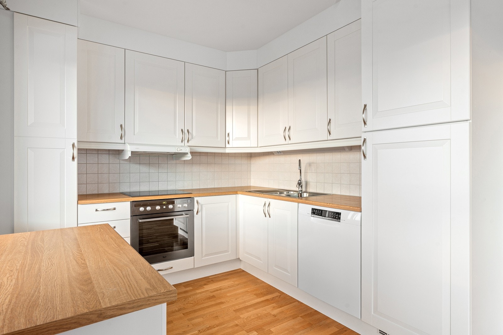 Tidløst kjøkken med ekstra benkeplass under vindu.