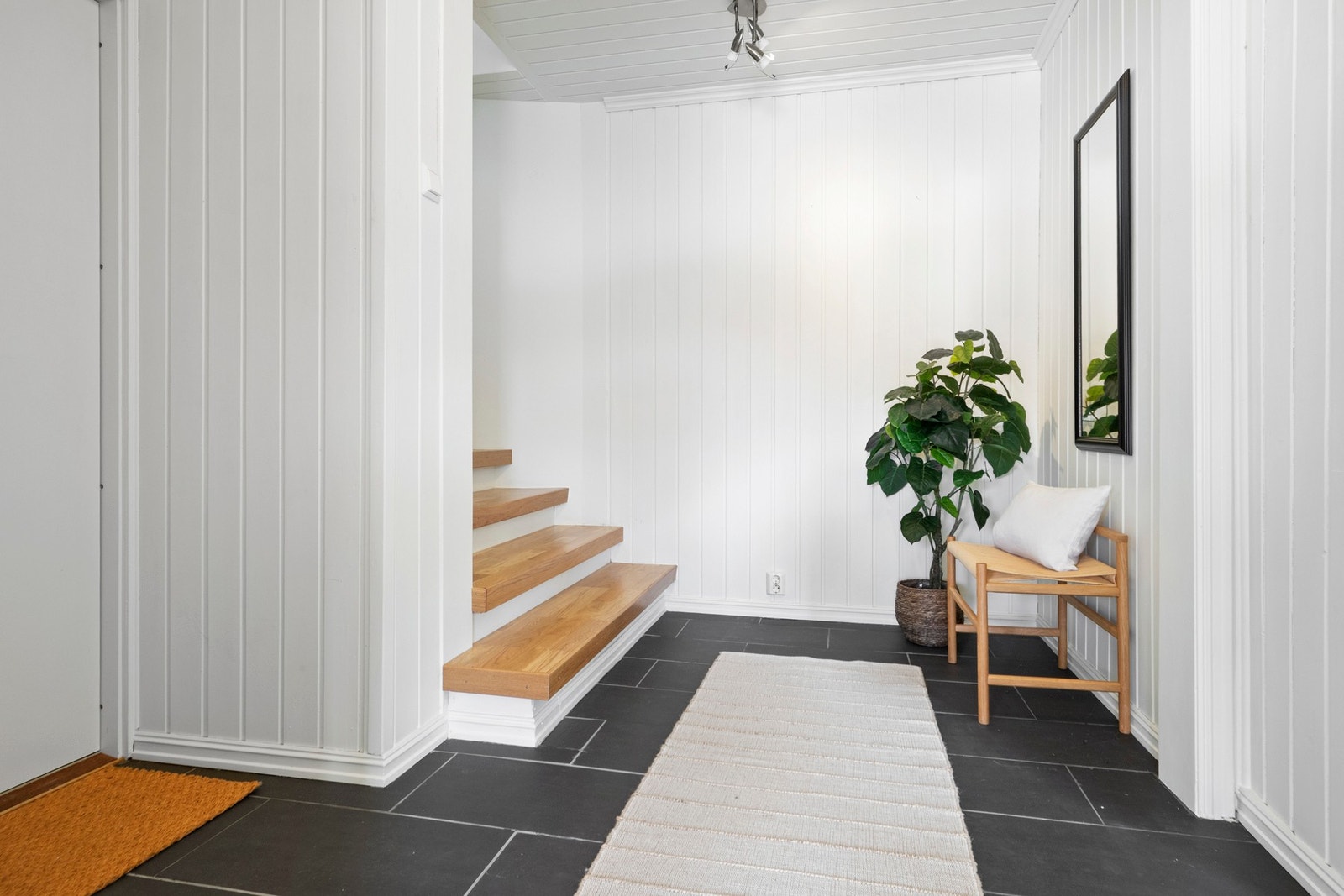 Gulvfliser med varme og hvitmalte panelvegger. Galleribilde