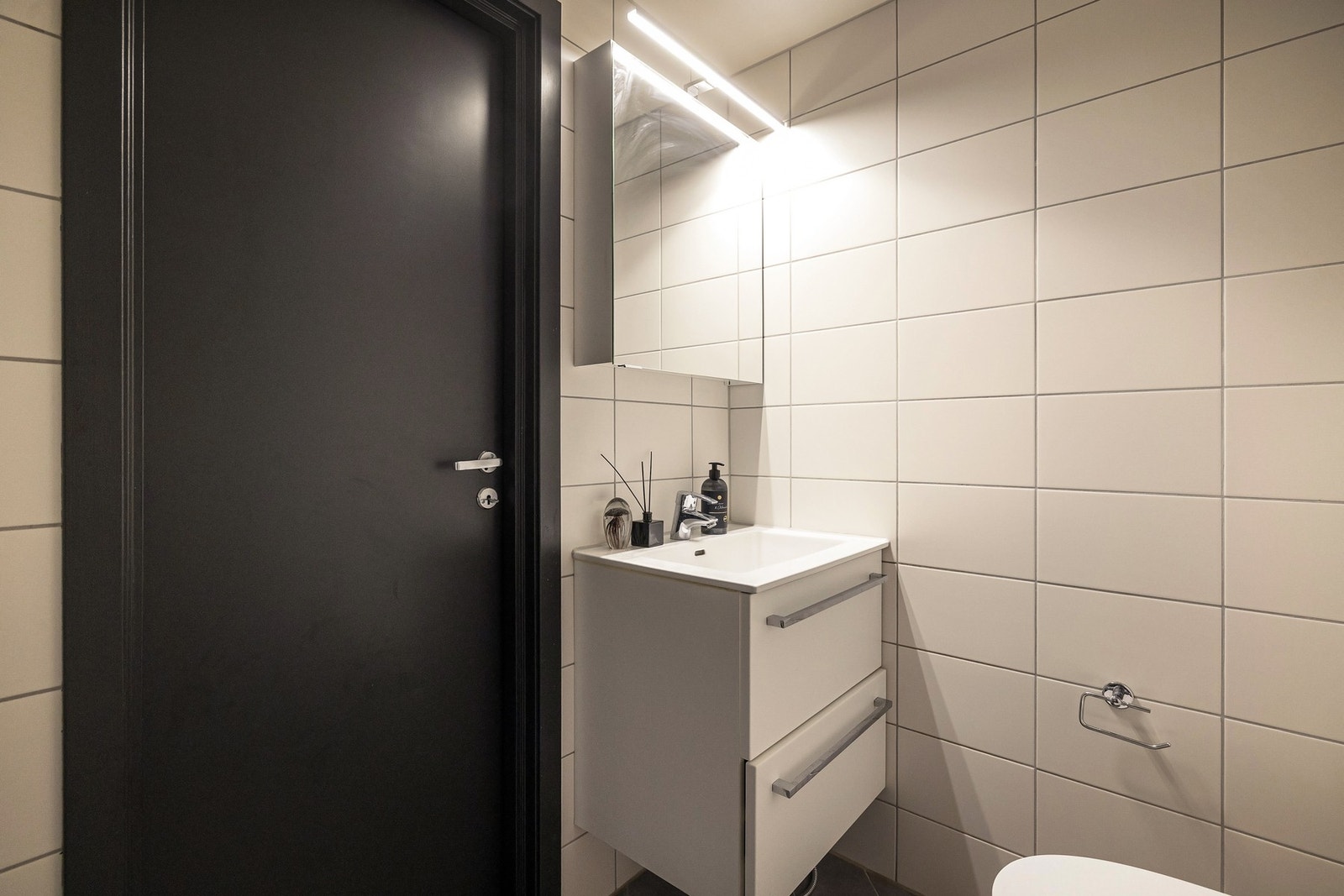 Badet er helfliset med lyse vegg og gulvflater som gir et rent og tidløst uttrykk, kombinert med hvitmalt, slett himling som bidrar til en luftig romfølelse. Galleribilde