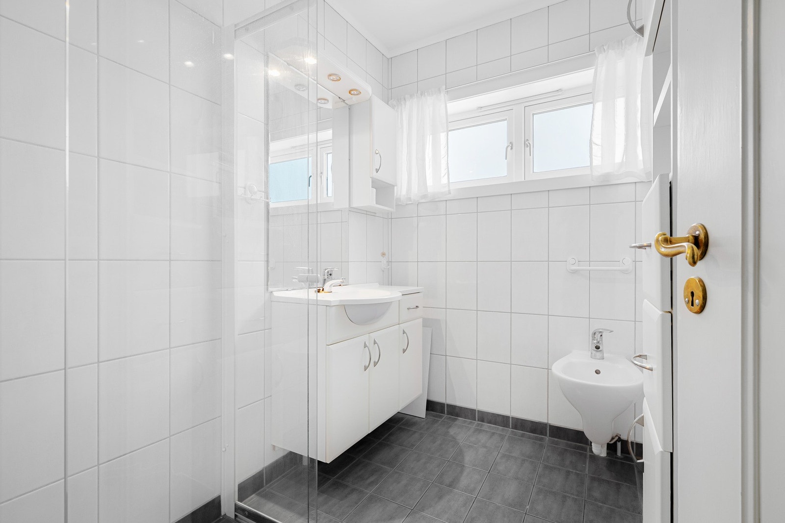 Badet er fra ca. 2010 med flislagte overflater, dusjhjørne med glassvegger og servantinnredning. Galleribilde